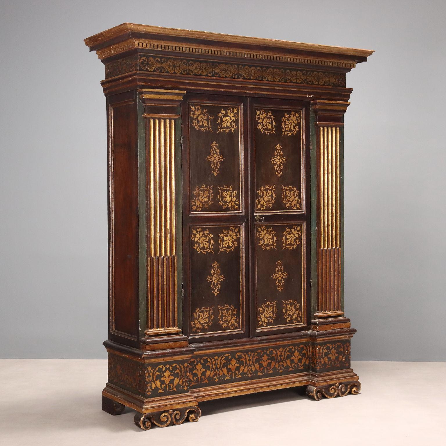 Armadio Manierista in noce laccato, con parti in noce, parti dipinte e parti dorate a foglia oro. Fronte con coppia di ante esternamente bipartite,  decorazioni fogliacee dorate nelle partiture, internamente decorate a tempera con scene