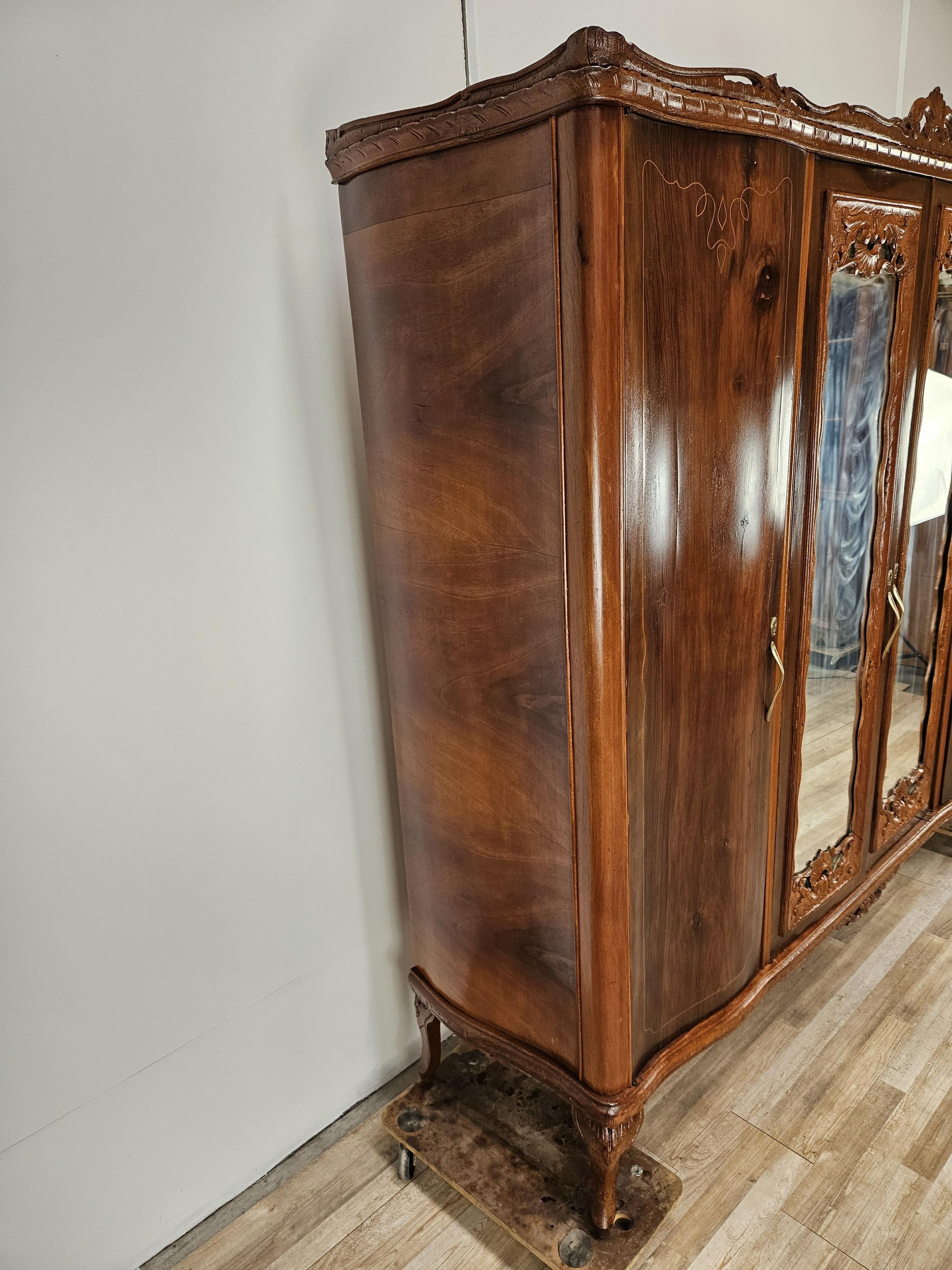 Elegante armario de nogal estilo Chippendale con varias decoraciones talladas y trabajadas, producción italiana circa 1930s.

Equipado con cuatro puertas de las cuales la derecha y la del medio están equipadas con una barra de colgar, la puerta