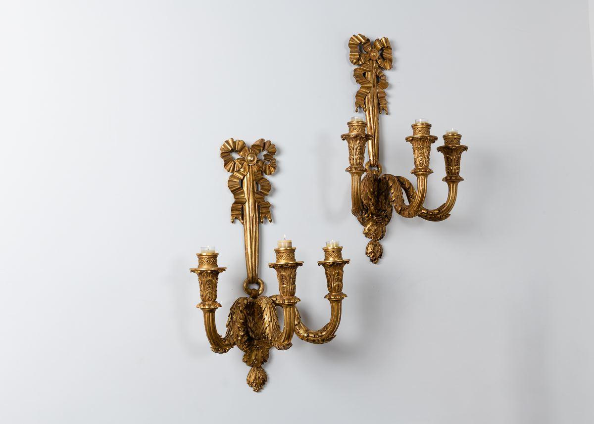 A pair of decadent gilt wood candelabras dating from the 1920s and carved to appear like beautiful, well arranged, cascading ribbons.
     