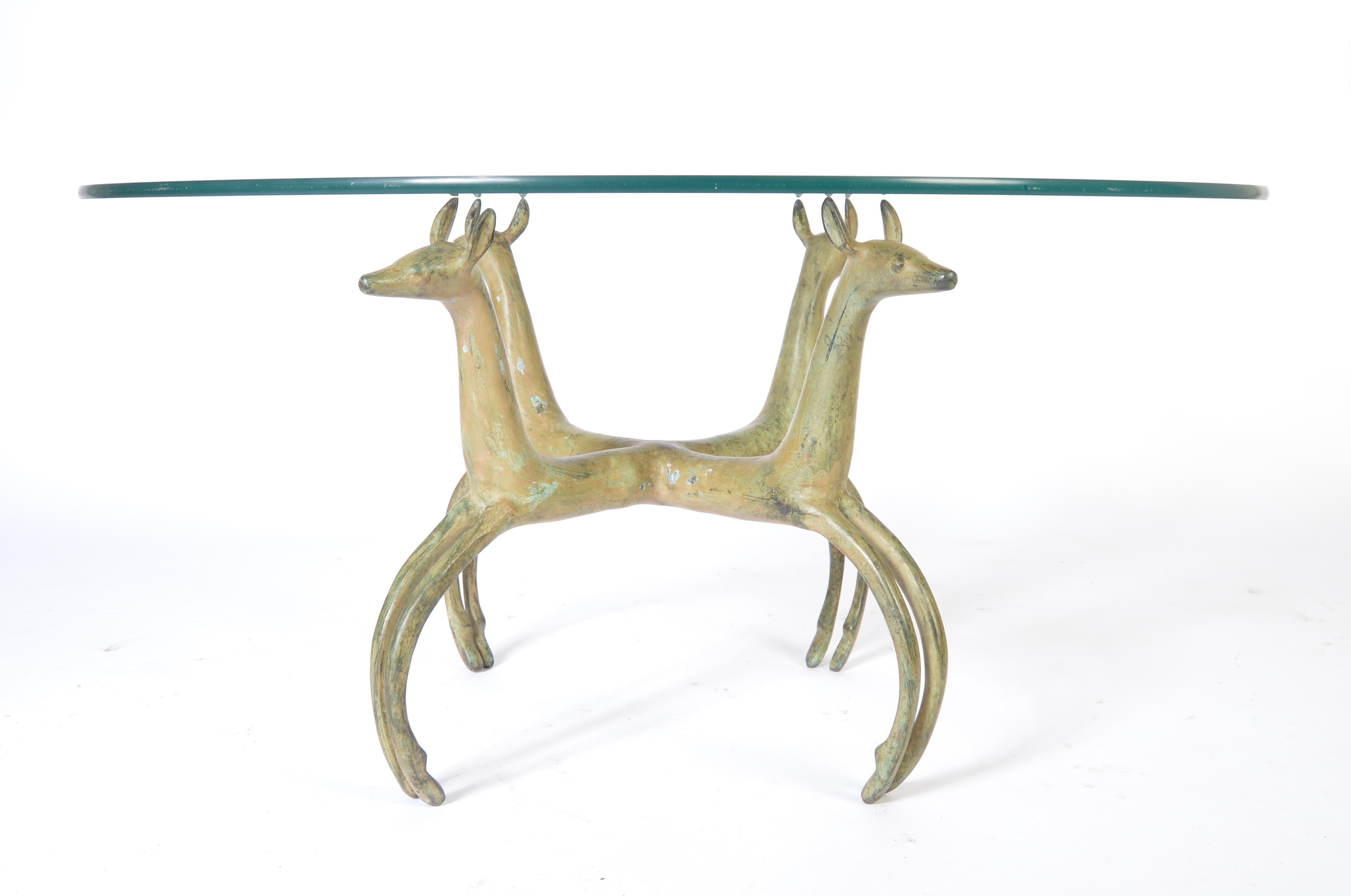 Bronze sculpture base of four deer set beneath a glass top.
Measures: Sculpture width is 24