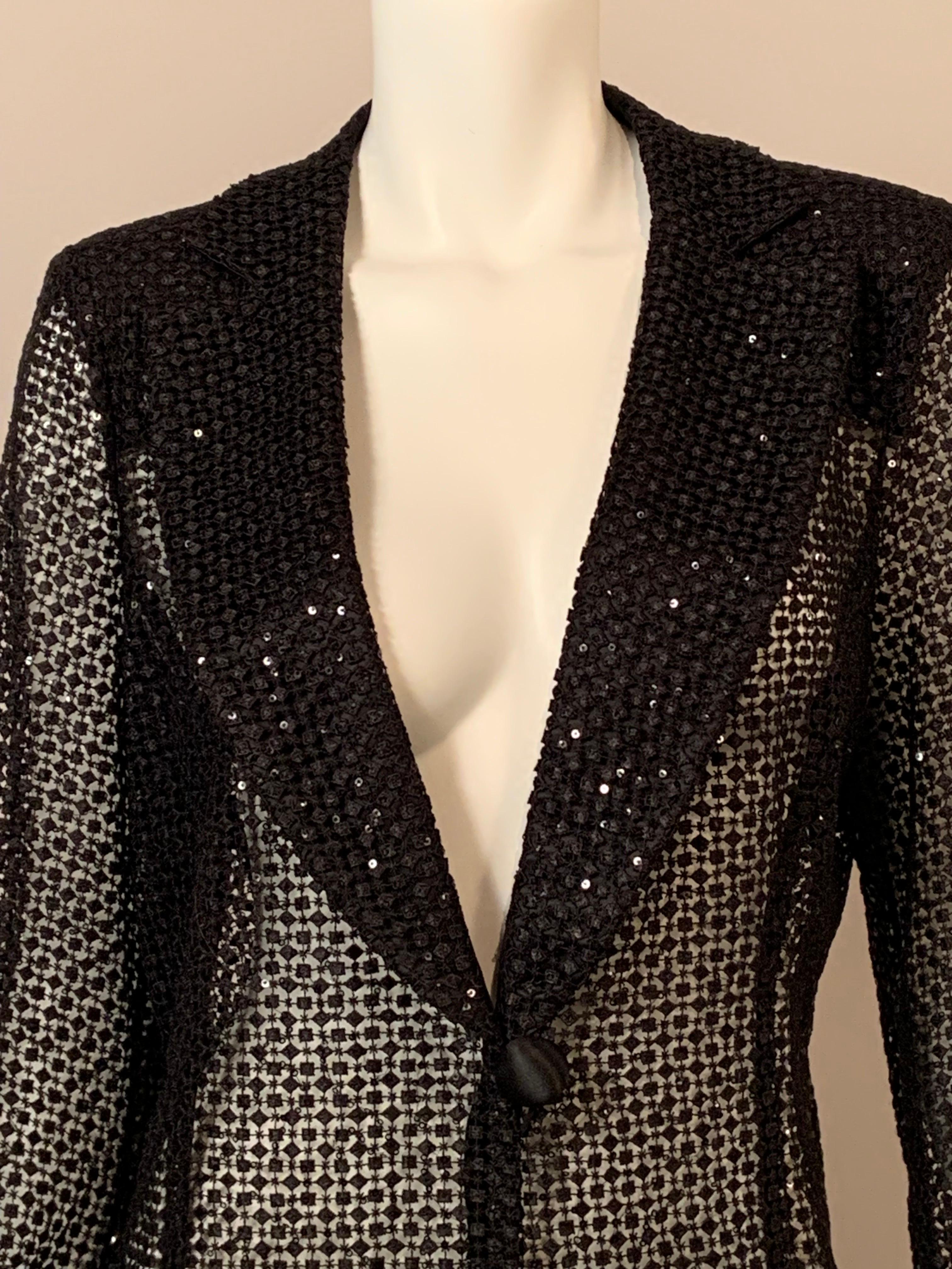 This sparkling Armani jacket has black satin lapels, cuffs and a single button and loop closure. The lapels are covered with the open work fabric used for the body of the jacket. The fabric is embellished with black sequins adding another layer of