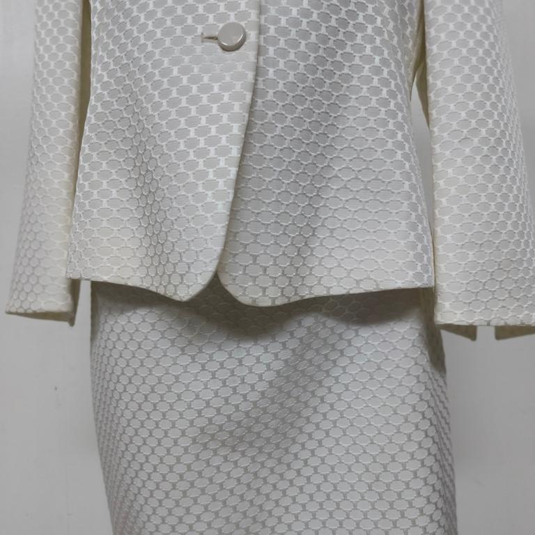 Tailleur gonna Armani Collezioni in broccato misto viscosa avorio, taglia IT 44 (≈ US 10 / EU 40-42), primi anni 2000. Realizzato in un broccato geometrico a piccoli esagoni che riflette delicatamente la luce, il completo fonde la pulizia delle