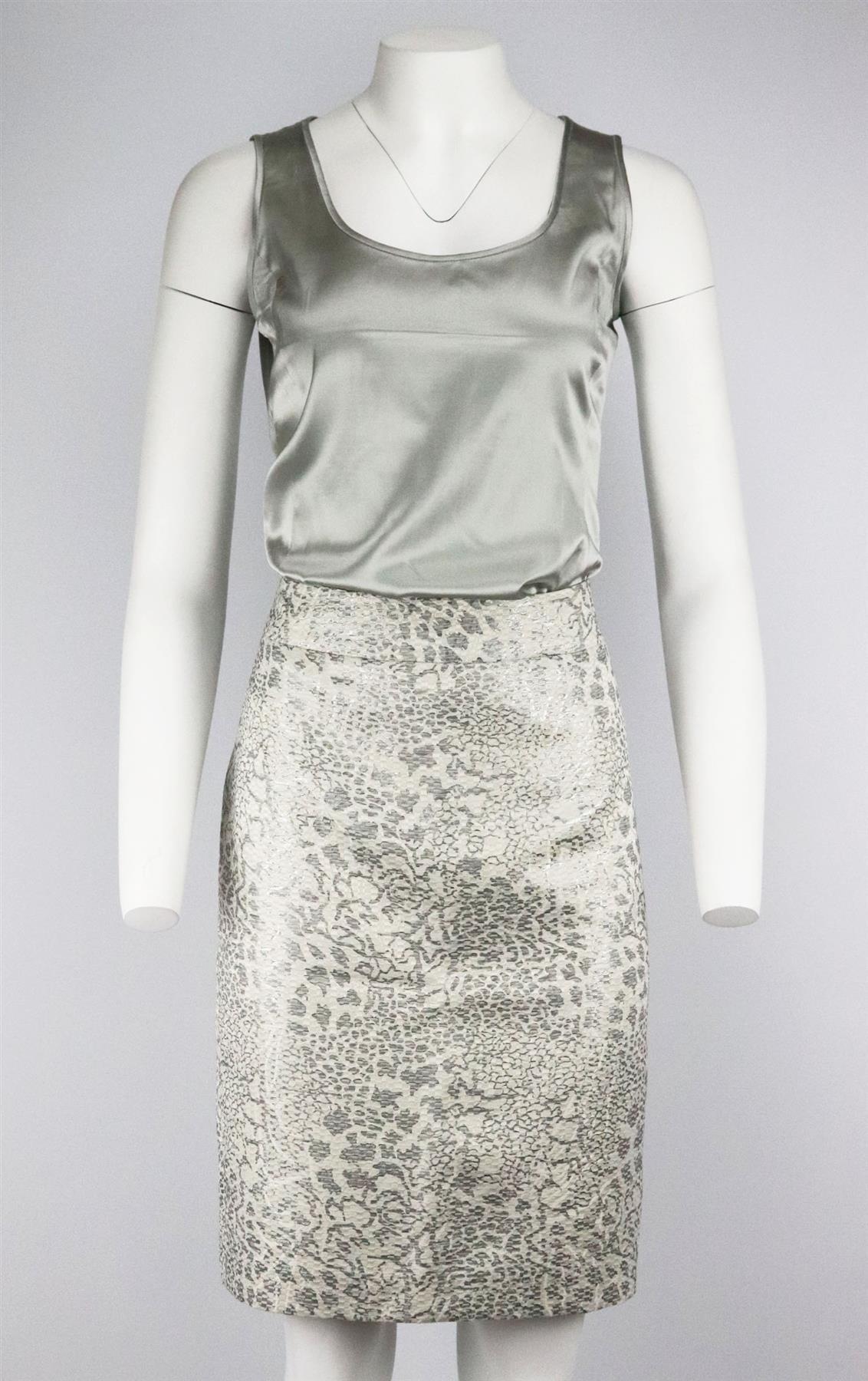 This vintage skirt, jacket and top set by Armani Colleszioni is made from metallic-silver and cream jacquard textured print skirt and jacket with ruffle detail along the neck, it also comes with satin top. Metallic-silver and cream polyester. Button