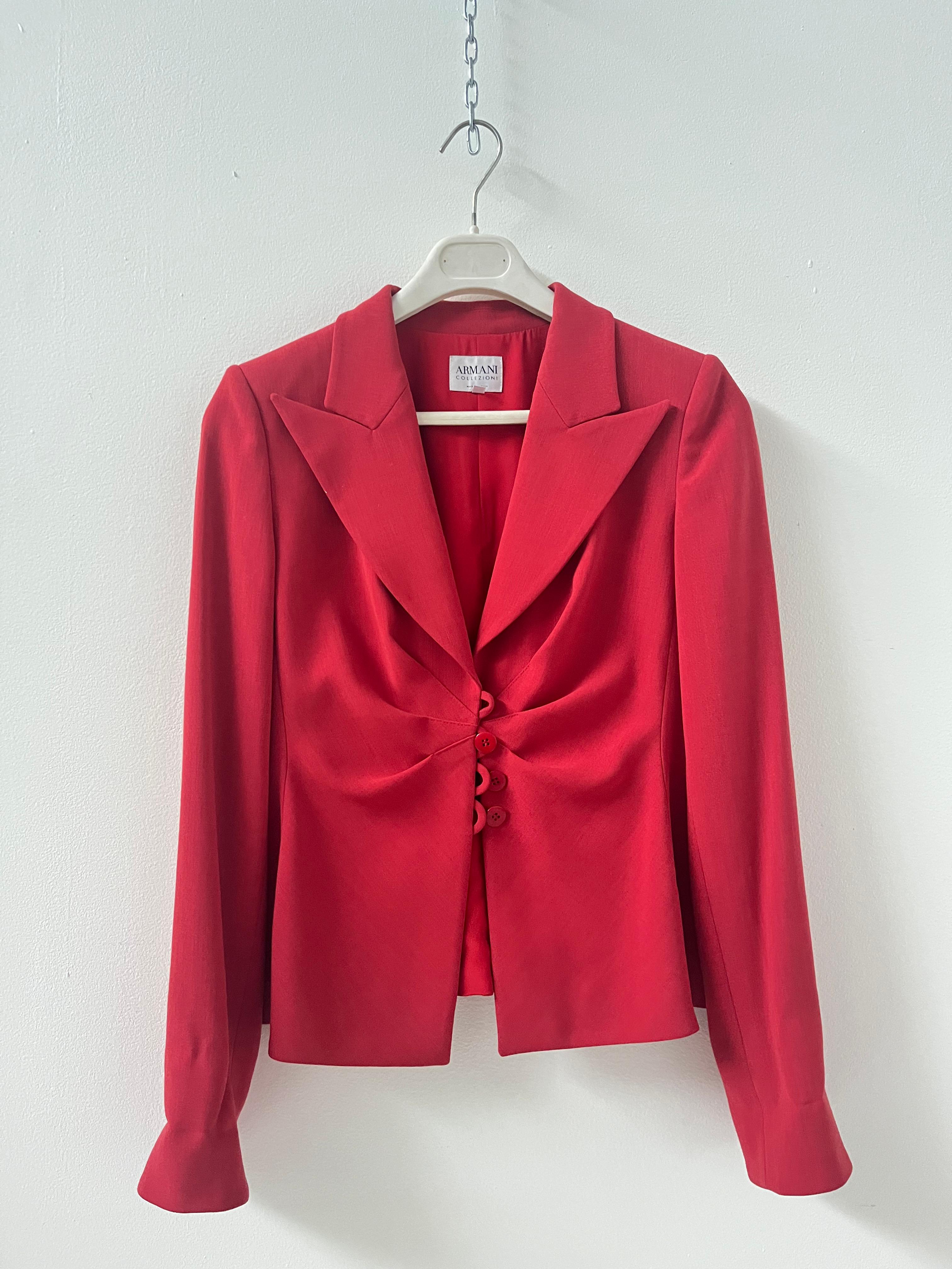 This stunning red blazer by Armani Collezioni embodies the timeless elegance that defines the Italian fashion house. Crafted from a luxurious blend of virgin wool and viscose, the fabric offers a silky touch and gracefully enhances the female