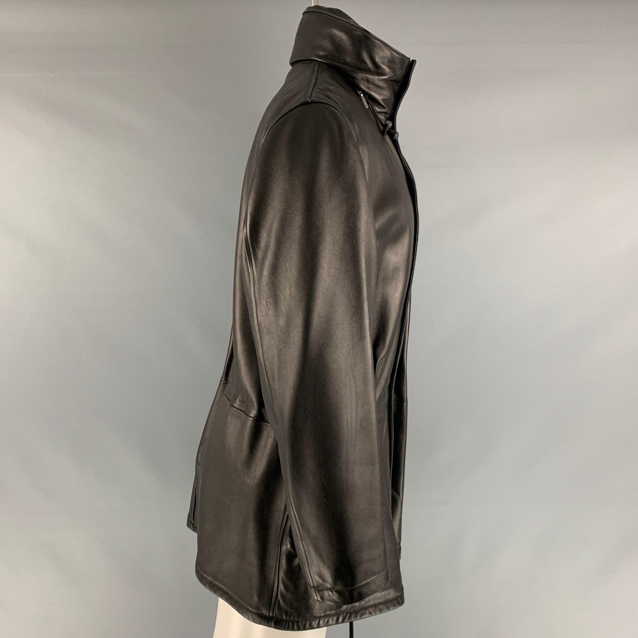 ARMANI COLLEZIONI oversized parka jacket in a black lamb skin nappa leather featuring a high neck, hidden hood, front pockets, drawstring details, and a hidden snap button closure. Made in Italy. Very Good Pre-Owned Condition. Minor signs of wear.