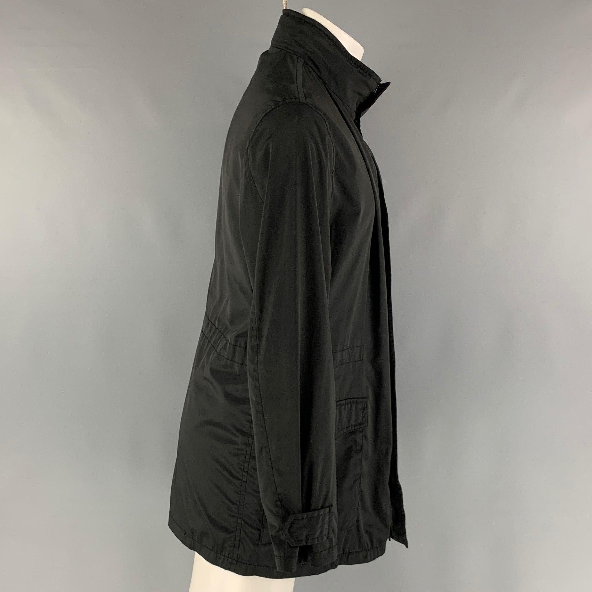 ARMANI COLLEZIONI windbreaker jacket comes in a black polyester water repellent woven material featuring a park style, patch pockets, internal hood, and a zip up and snap button closure. Excellent Pre-Owned Condition. 

Marked:   40 

Measurements: