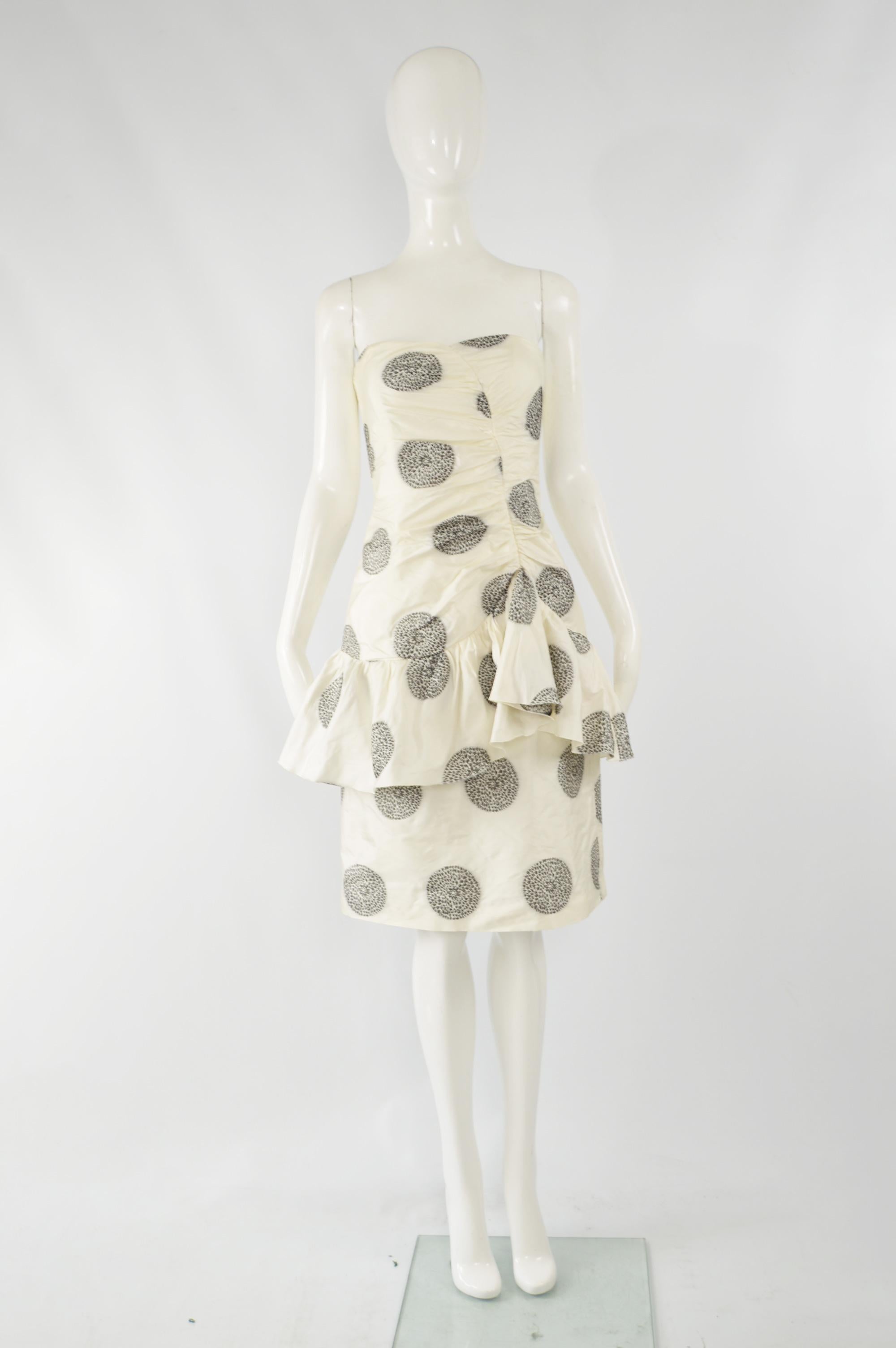 A fabulous womens pre owned Armani collezioni cocktail party dress in a white silk blend with a black floral pattern. It is strapless with a flattering ruffle/ peplum effect at the hips. 

Size: Marked IT 42 but fits more like a UK 8/ US 4/ EU 36.