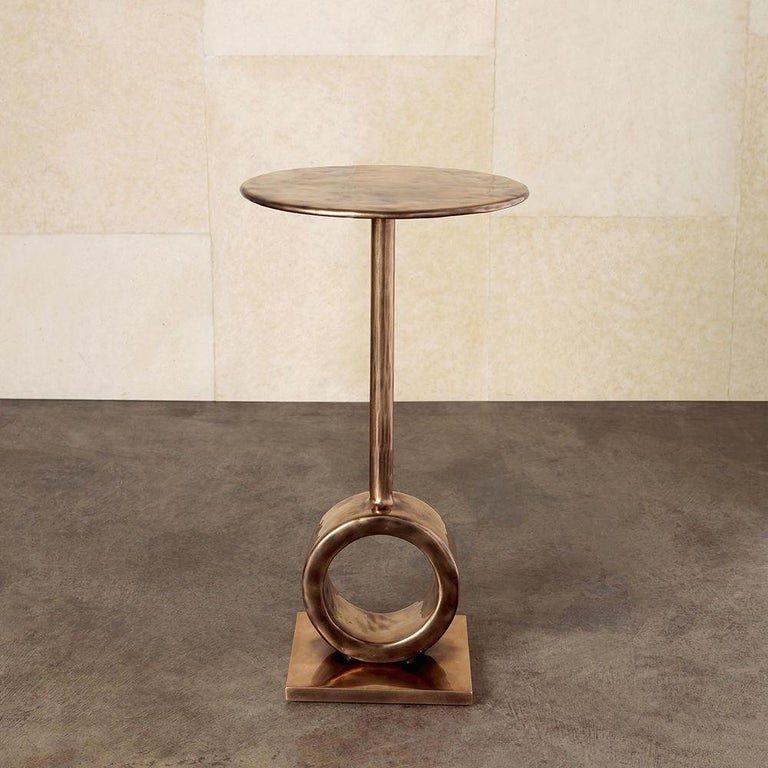 This petite cocktail table is artfully cast in solid bronze and features a mottled, hand hewn surface texture. The cylindrical base and delicate stem lend the piece a sculptural quality. The foundry is based in Illinois and specializes in sculptural