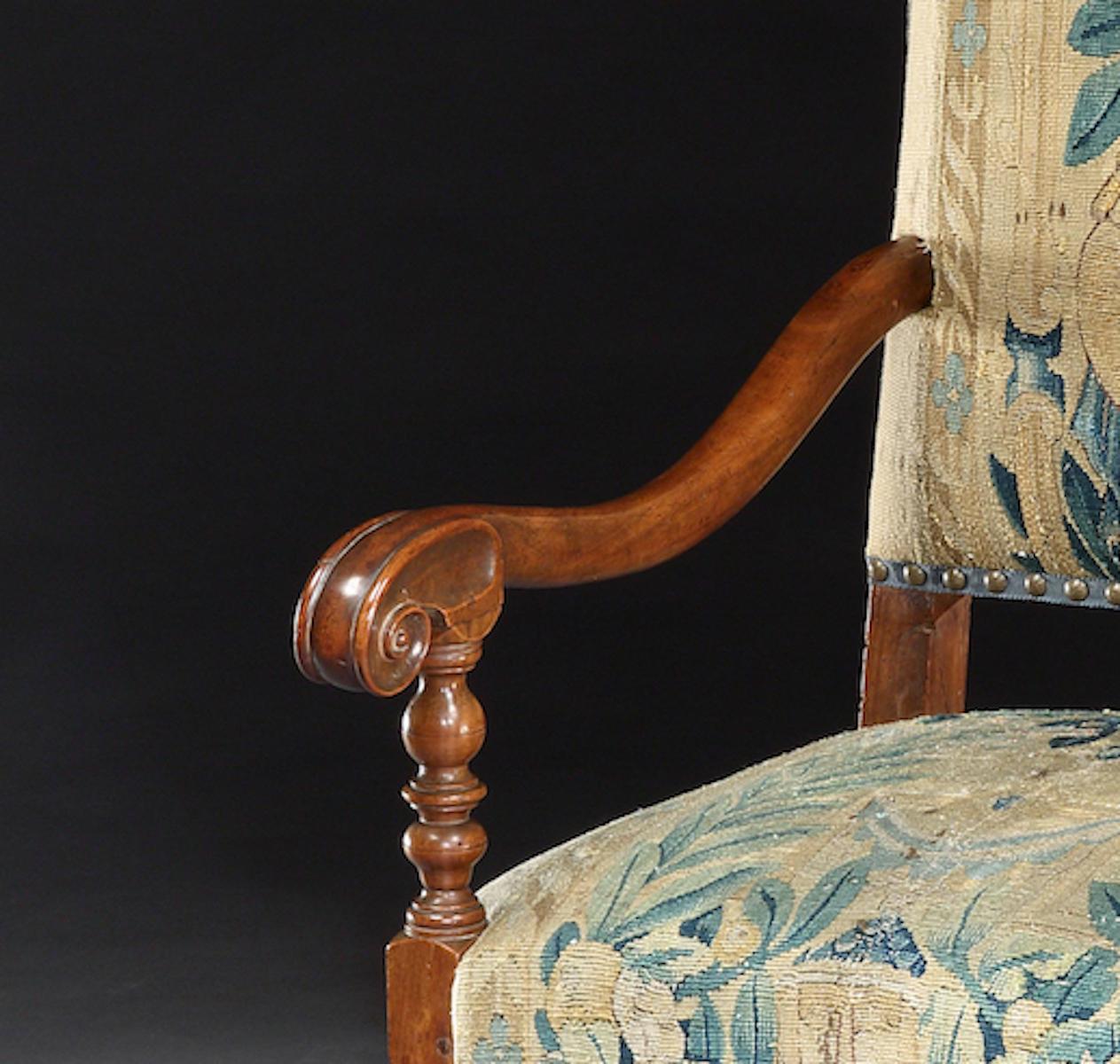 This elegant armchair exudes classic gravitas, with scroll arms, fall turnings and triple toe feet

The tapestry back depicting Flora underneath a bower is a distinctive feature.  It has been removed cleaned and conserved so that it is stable and