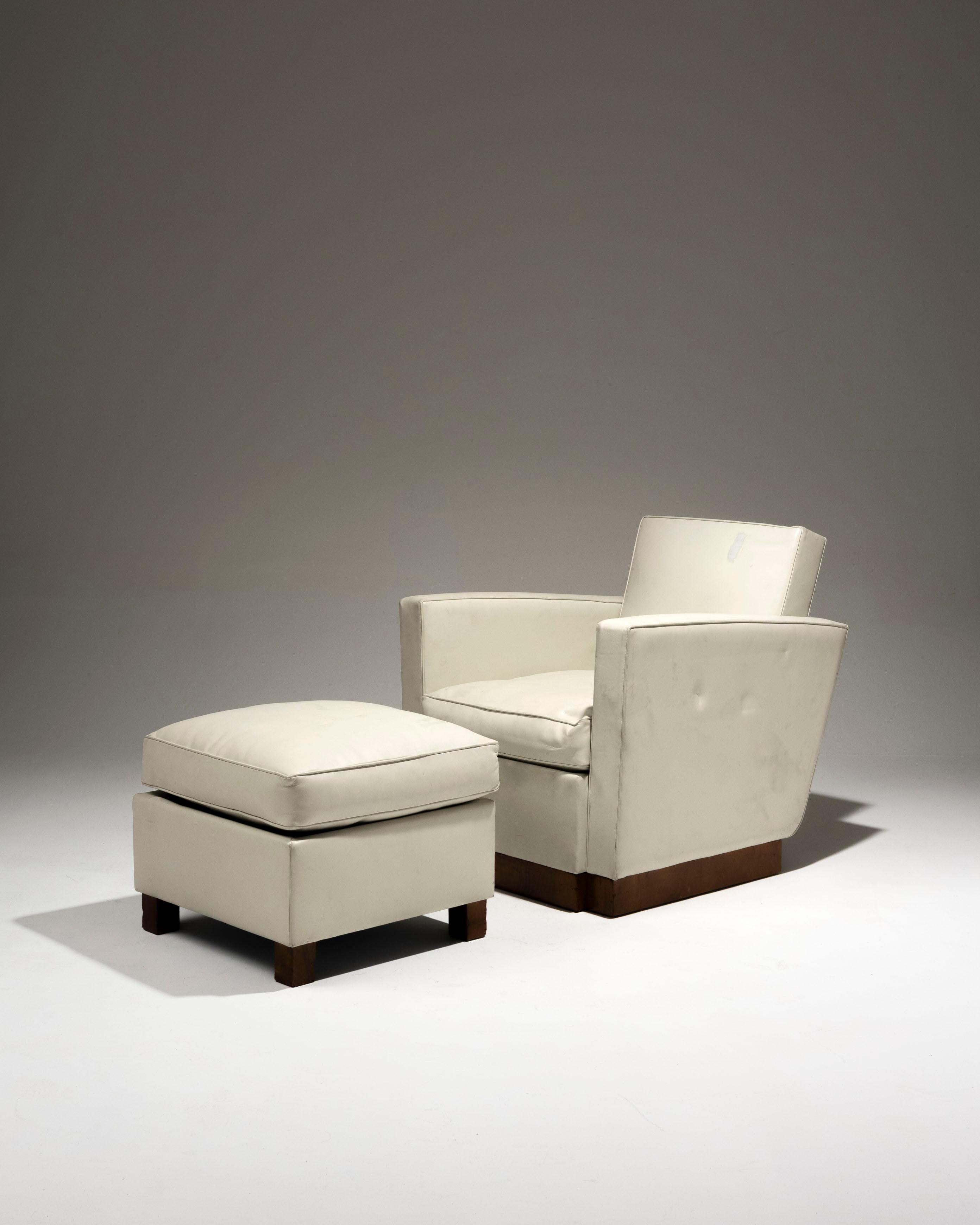 Armchair and ottoman covered in off-white leather, by French architect and designer Jacques Adnet (1900-1984) from the 1930s. The angled backrest is framed by two armrests. The solid base is veneered in walnut. The ottoman is covered with a feather