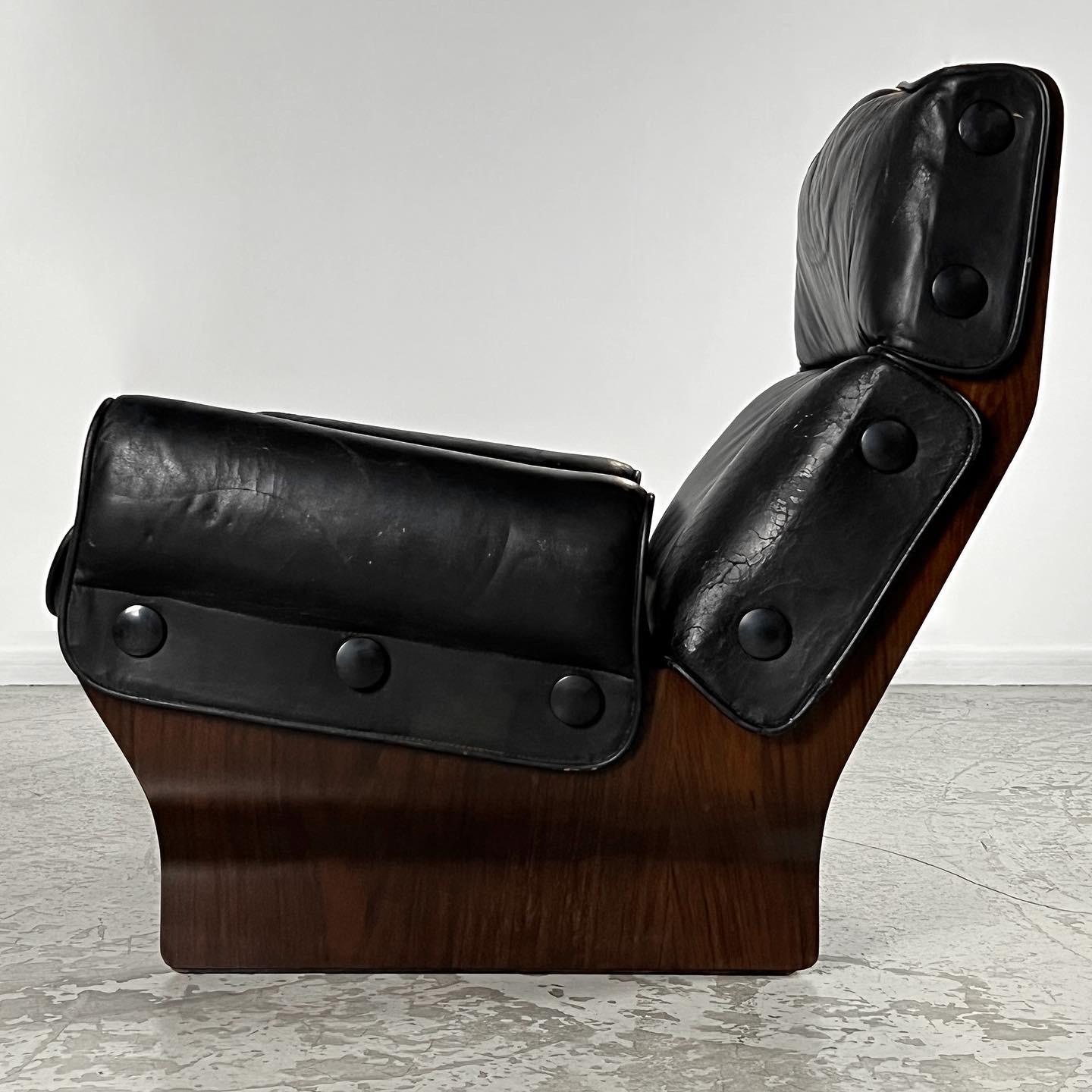 Very comfortable armchair and ottoman, with a beautifully curved wooden frame and original black leather cushions.
The cushions are attached to the frame by black buttons.
The frame is built of thick and solid plywood with a wood veneer