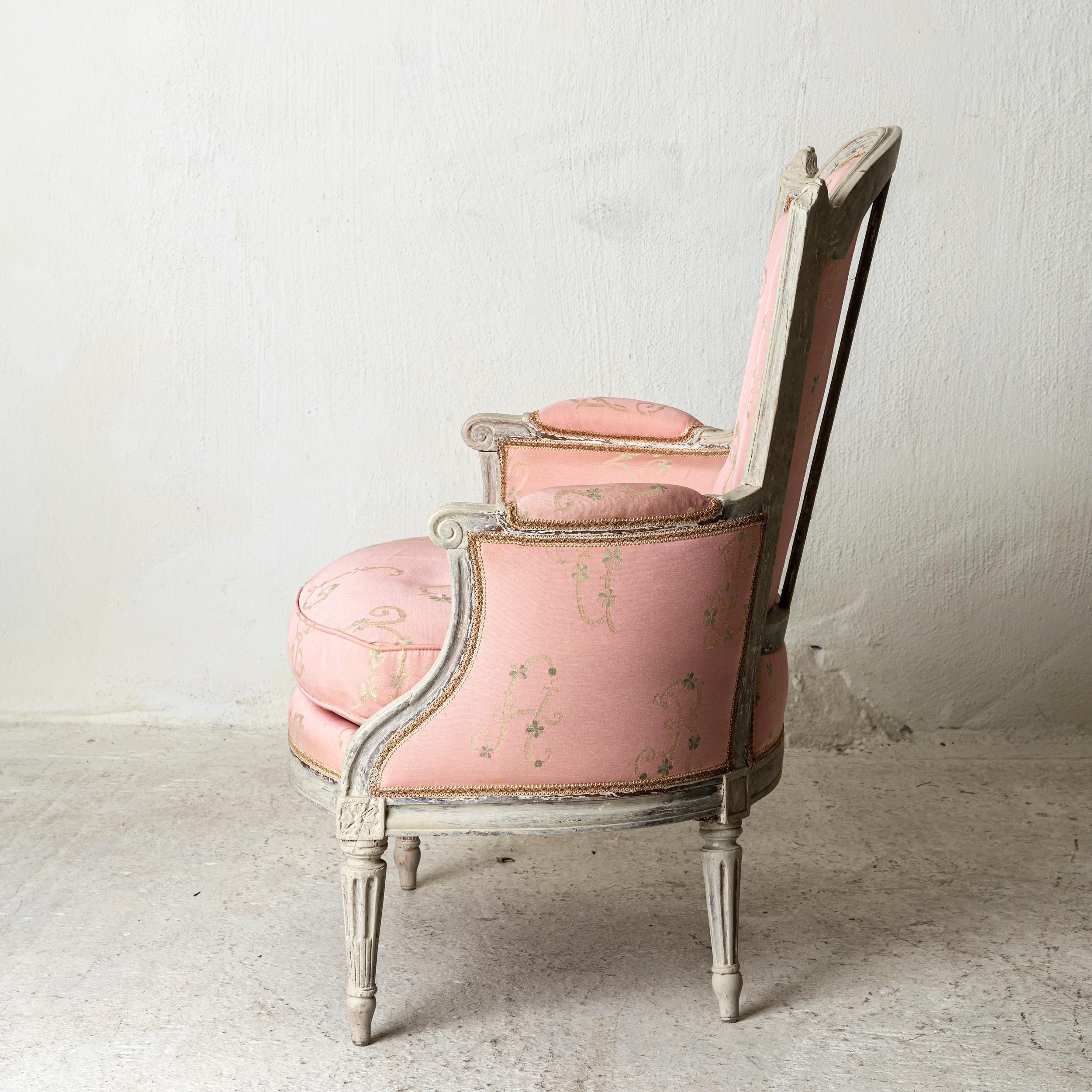 Chair bergère Louis XVI neoclassical French white pink France. An armchair bergère made during the Louis XVI period in France. Painted in a white finish. Channeled legs and armrests. Beautiful carvings in back and frieze. Upholstered in a light pink