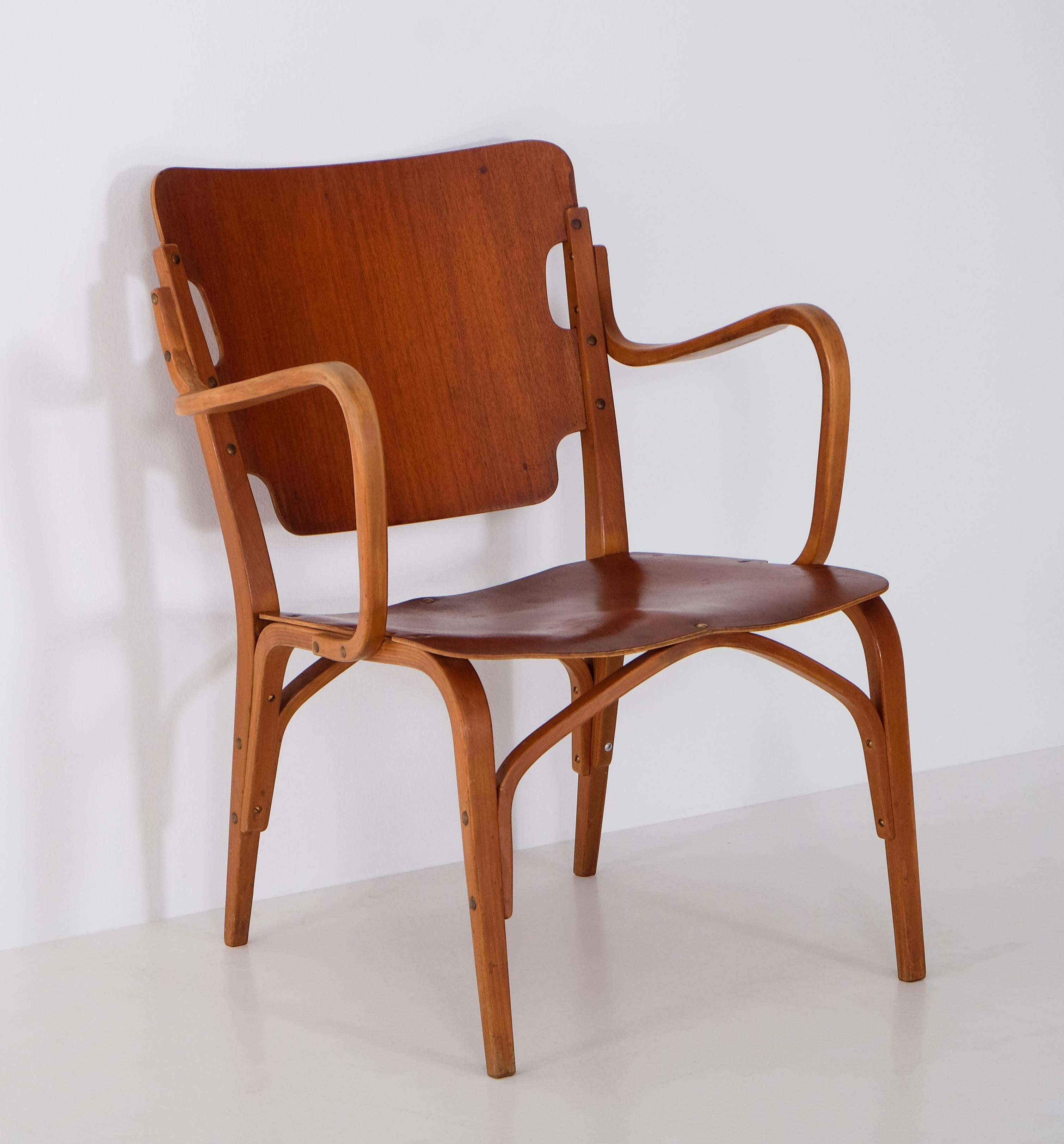 Raro sillón del diseñador sueco Carl-Axel Acking.
Patas y reposabrazos de haya, asiento y respaldo de chapa de caoba moldeada. 
Restos de etiqueta, también con la insignia de Ferd. Grandes almacenes Lundquist Gotemburgo. 
