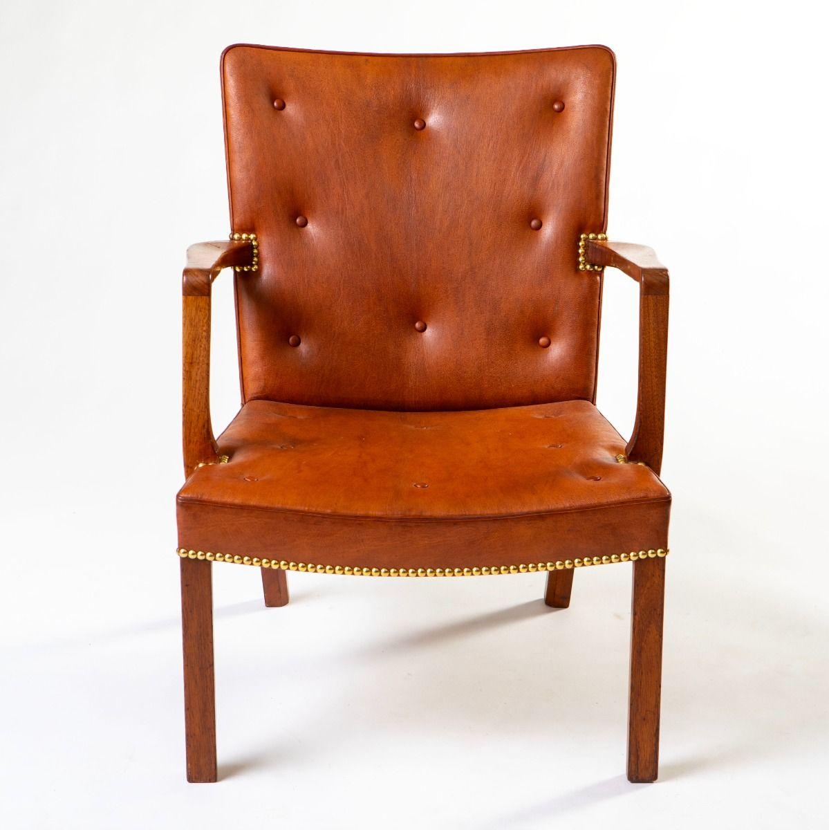 Poltrona realizzata in mogano massiccio e rivestita in pelle Niger con bottoni profondi. I bordi sono accentuati da eleganti punte di chiodi in ottone, un dettaglio decorativo raffinato che sottolinea la qualità artigianale della sedia. Prodotto