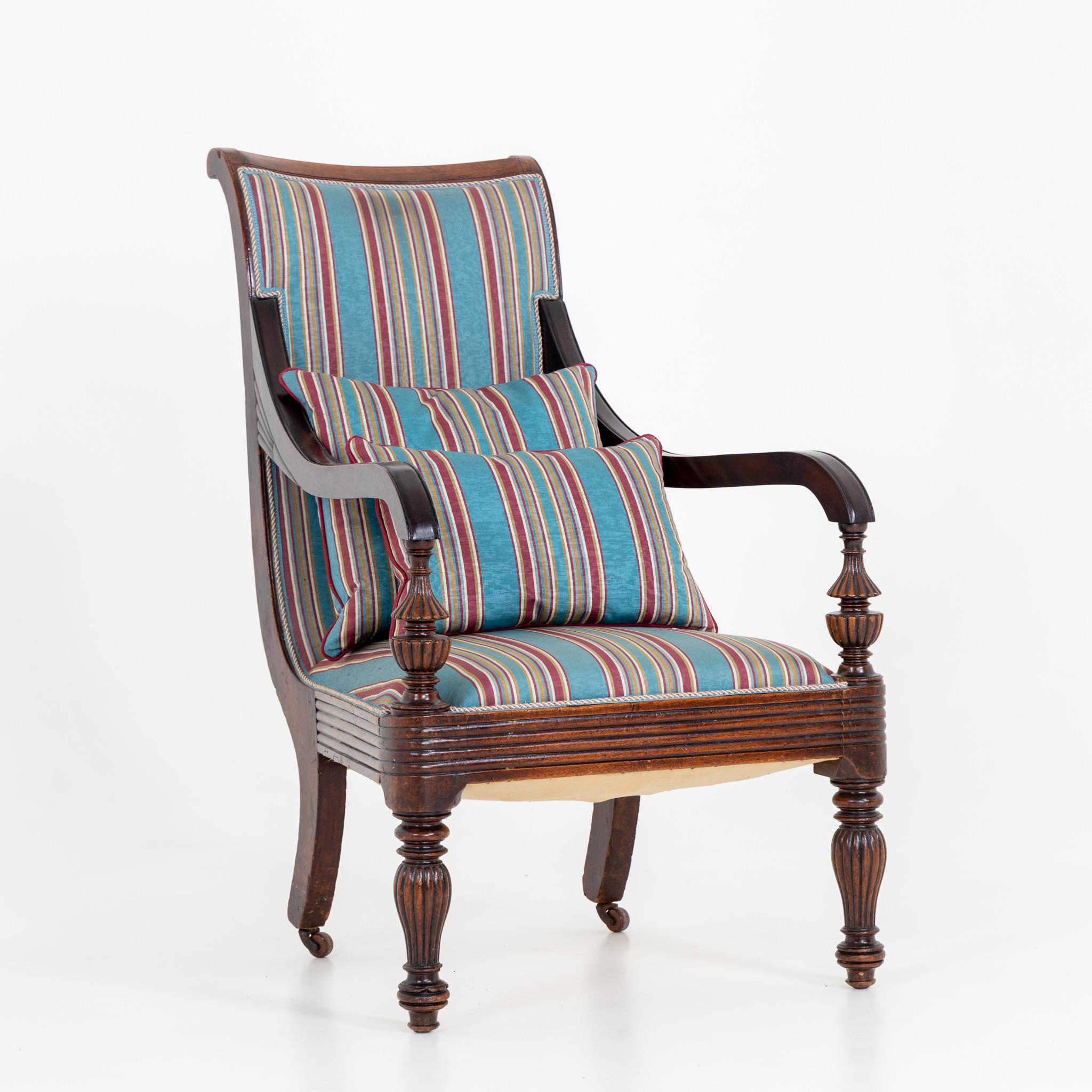 English mahogany armchair with striped upholstery. The rear legs are on brass castors.