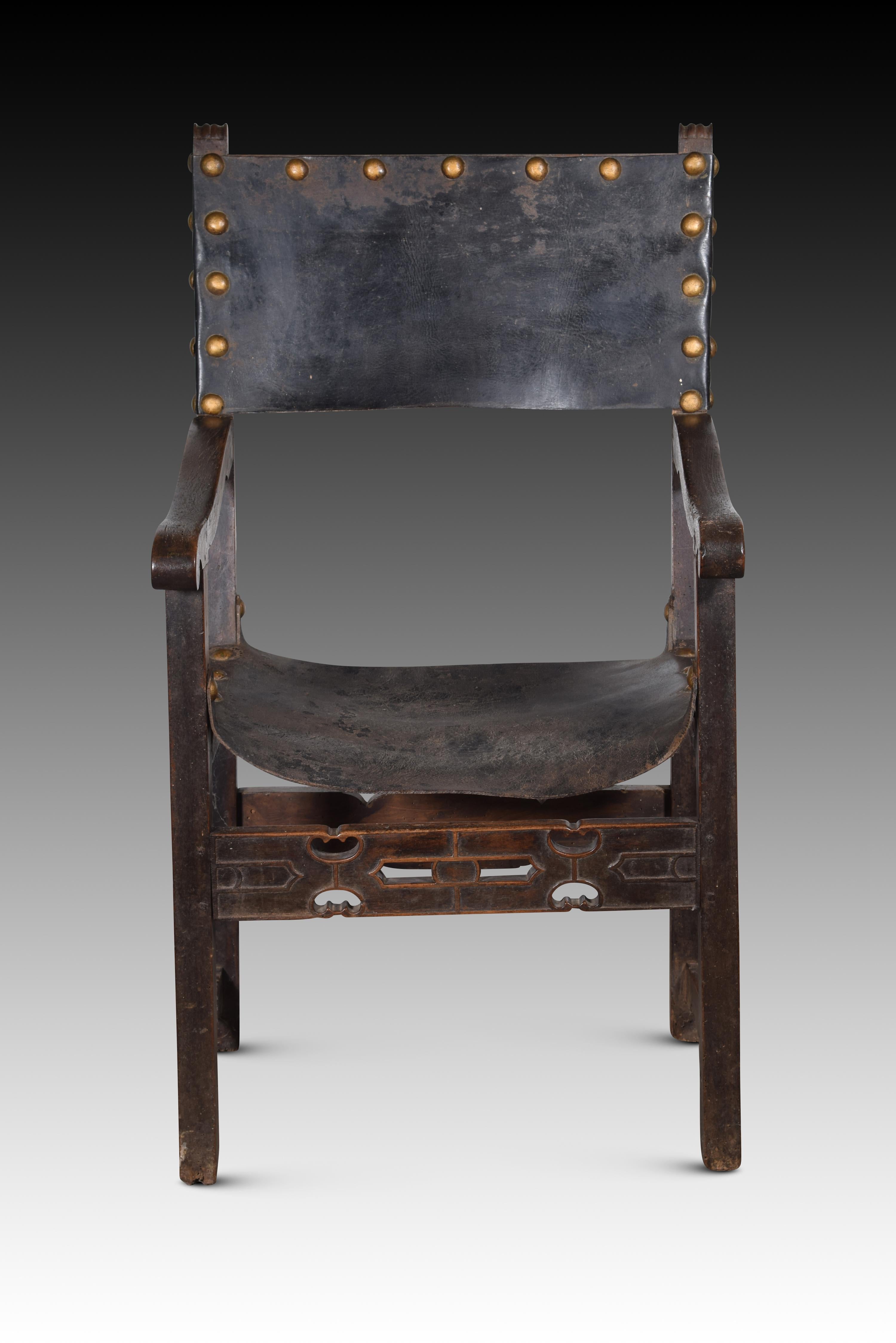 Friar armchair. Leather, walnut wood. Spain, 16th century. 
Armchair with arms and high back of the type known as “frailero”, which has studded leather on the seat and upper part of the back, low cut-out low profile chambrances joining the front