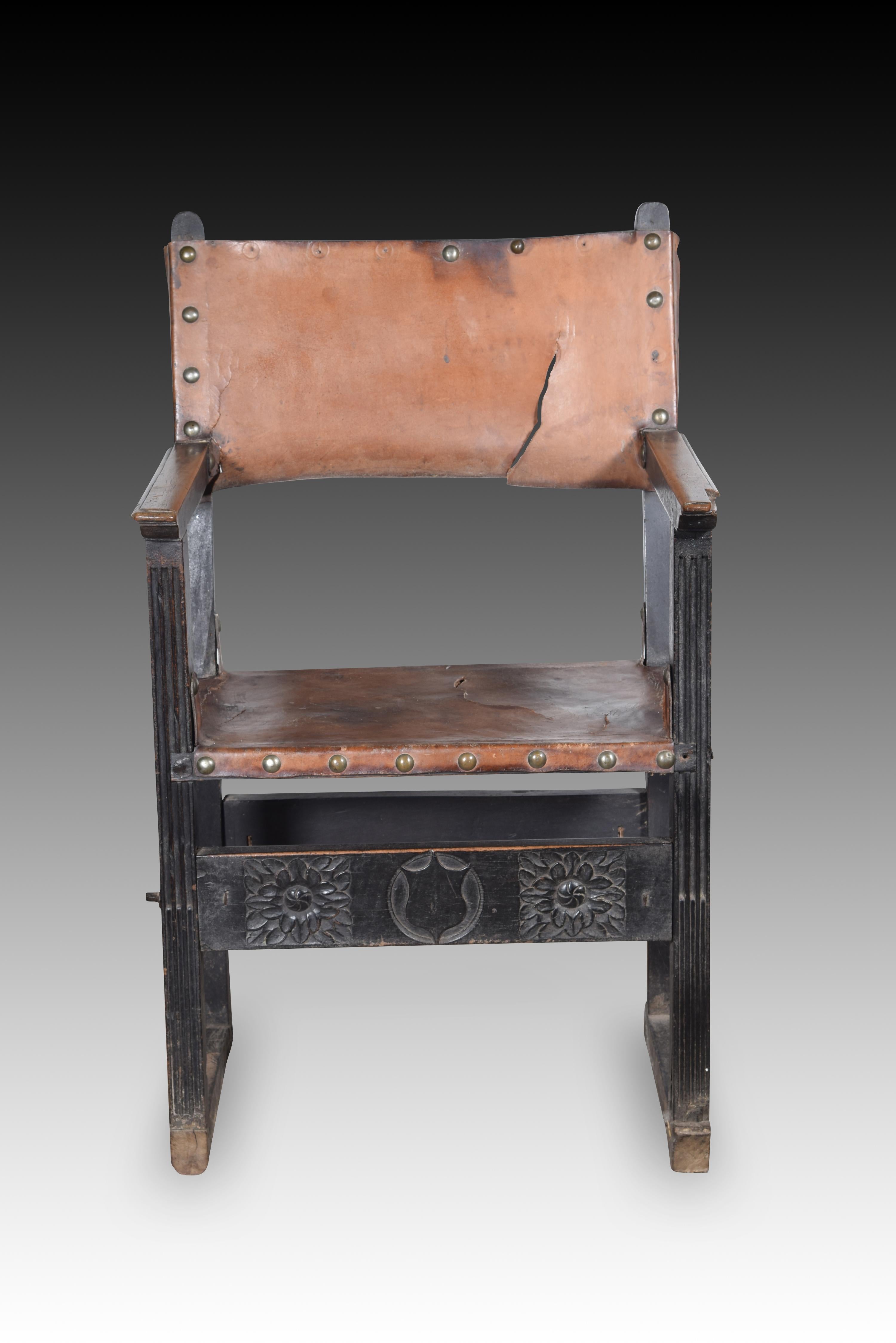 Friar armchair. Walnut wood, leather. Spain, 16th century. 
Armchair with arms and high back of the type known as “frailero”, which has leather with studs on the seat and upper part of the back, very low chambrances joining the front legs with the