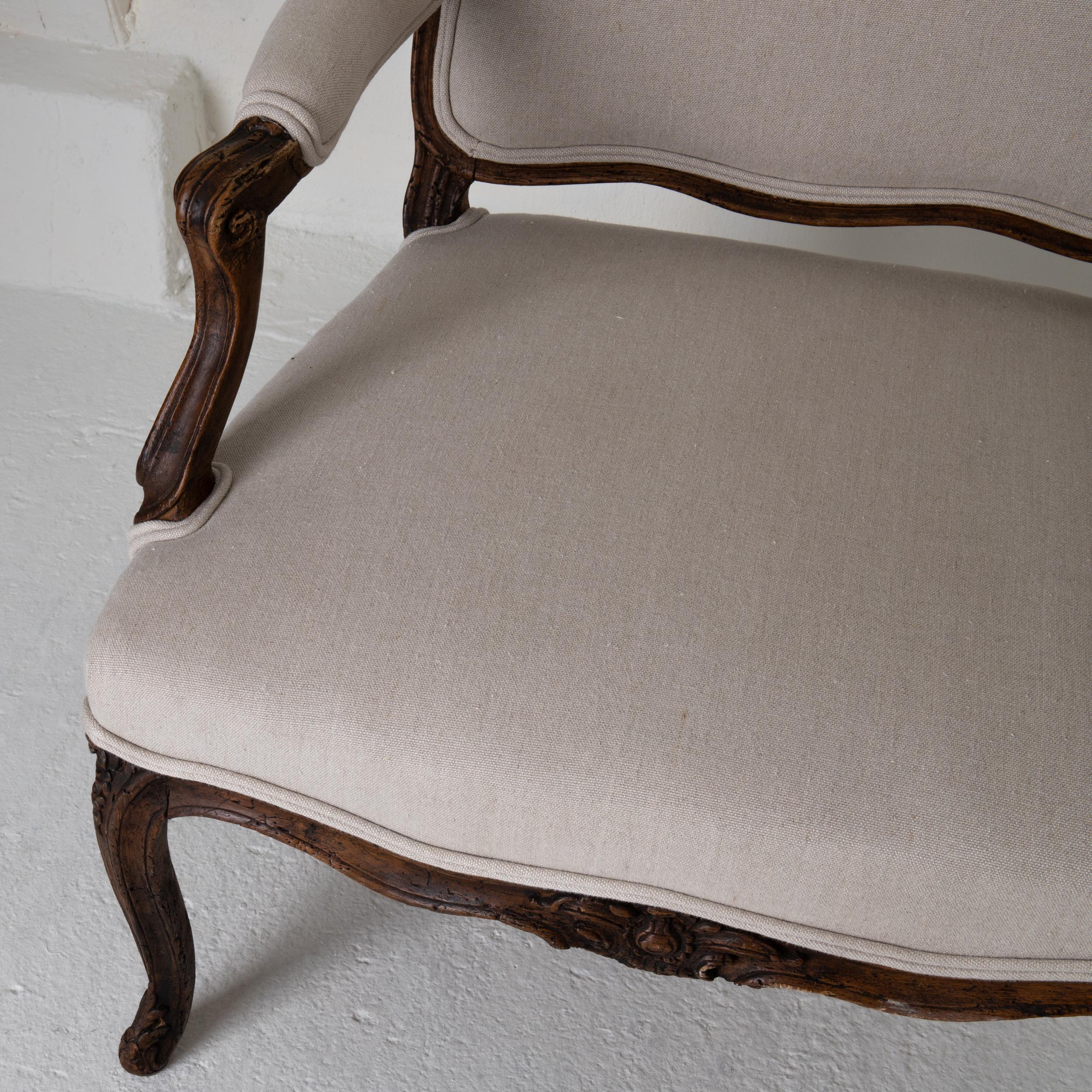 Armchair Swedish Rococo brown beige linen, Sweden. An armchair made during the Rococo period 1730-1750 in France. Carved oak frame in a dark brown. Upholstered back, seat and armrests in a neutral colored linen. Curved and carved S-shaped legs.