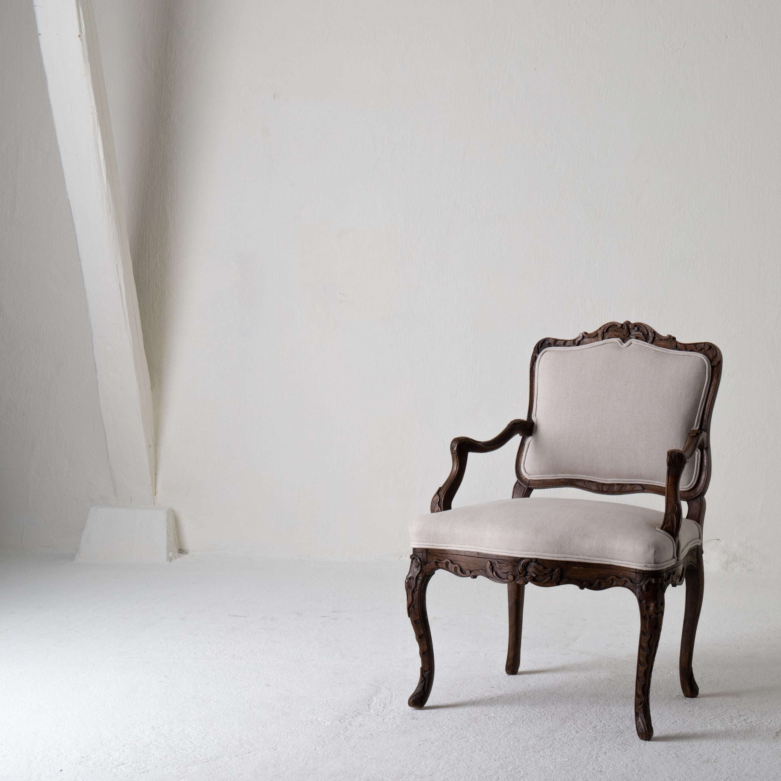 Armchair French Rococo brown beige linen France. An armchair made during the Rococo period in France, circa 1730. Frame made from carved oak.

 