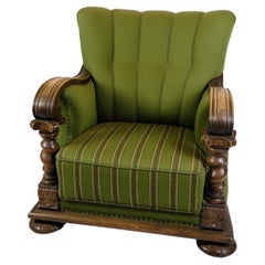 Sessel in grünem Stoff mit Holzschnitzereien aus den 1920er Jahren.
