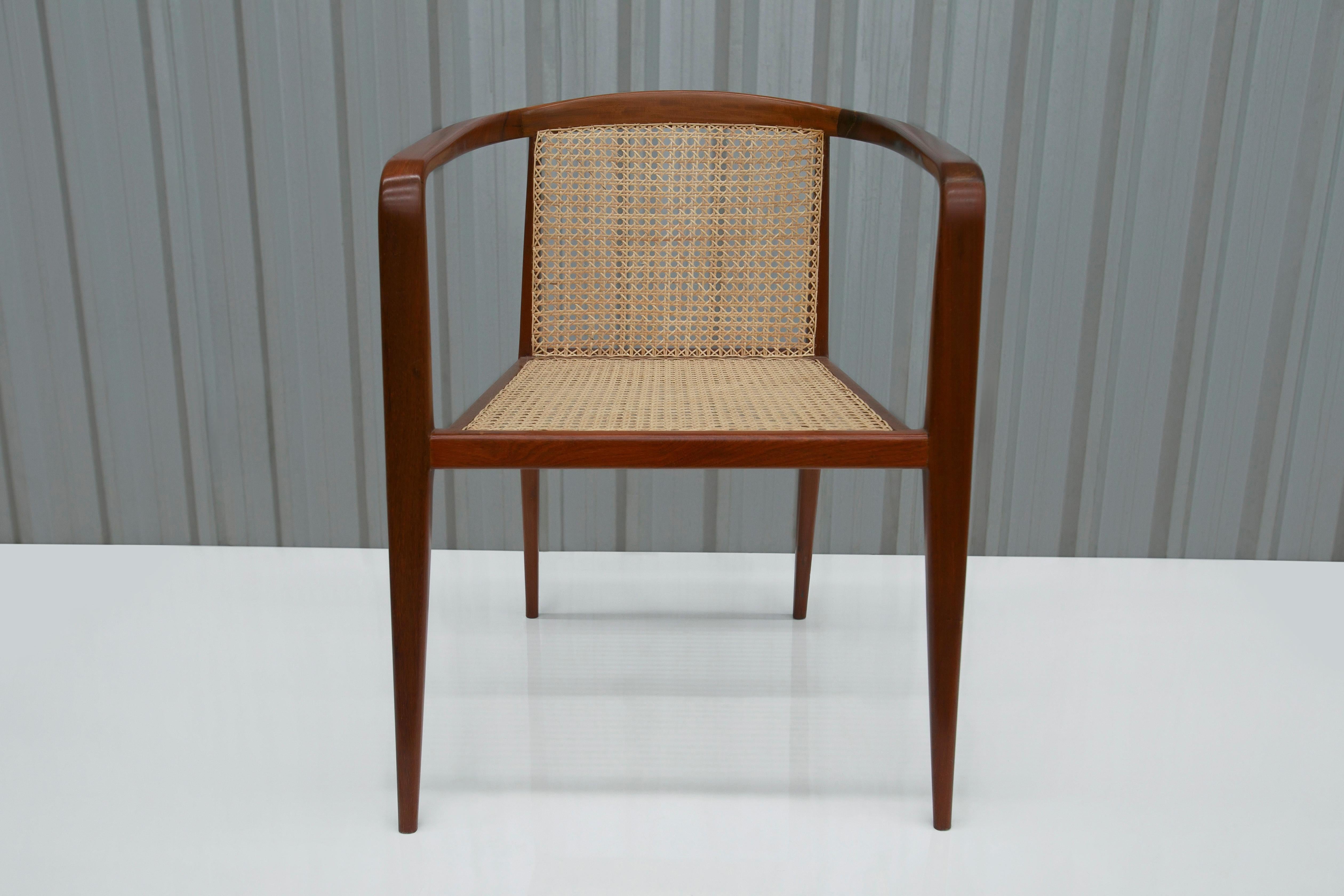 The chair is made of Brazilian rosewood (also known as jacaranda) and consists of four toothpick legs, a backrest in straw caning, and delicately curved armrests that connect to the backrest. Also, the wood on this piece has been refinished and