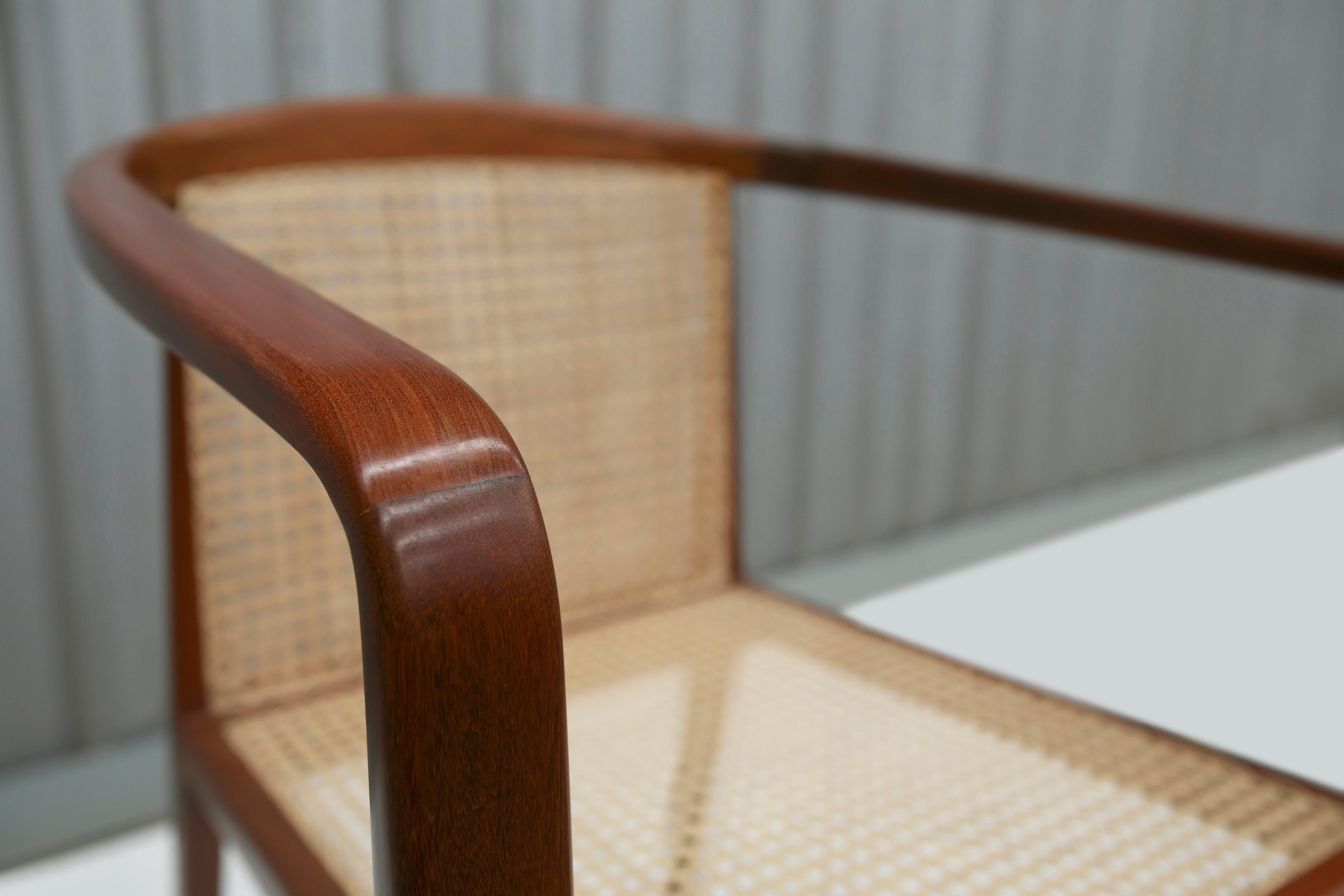 The chair is made of Brazilian Caviuna wood and consists of four toothpick legs, a backrest in straw caning, and delicately curved armrests that connect to the backrest. 

The wood on this piece has been refinished and the caning is new. This model