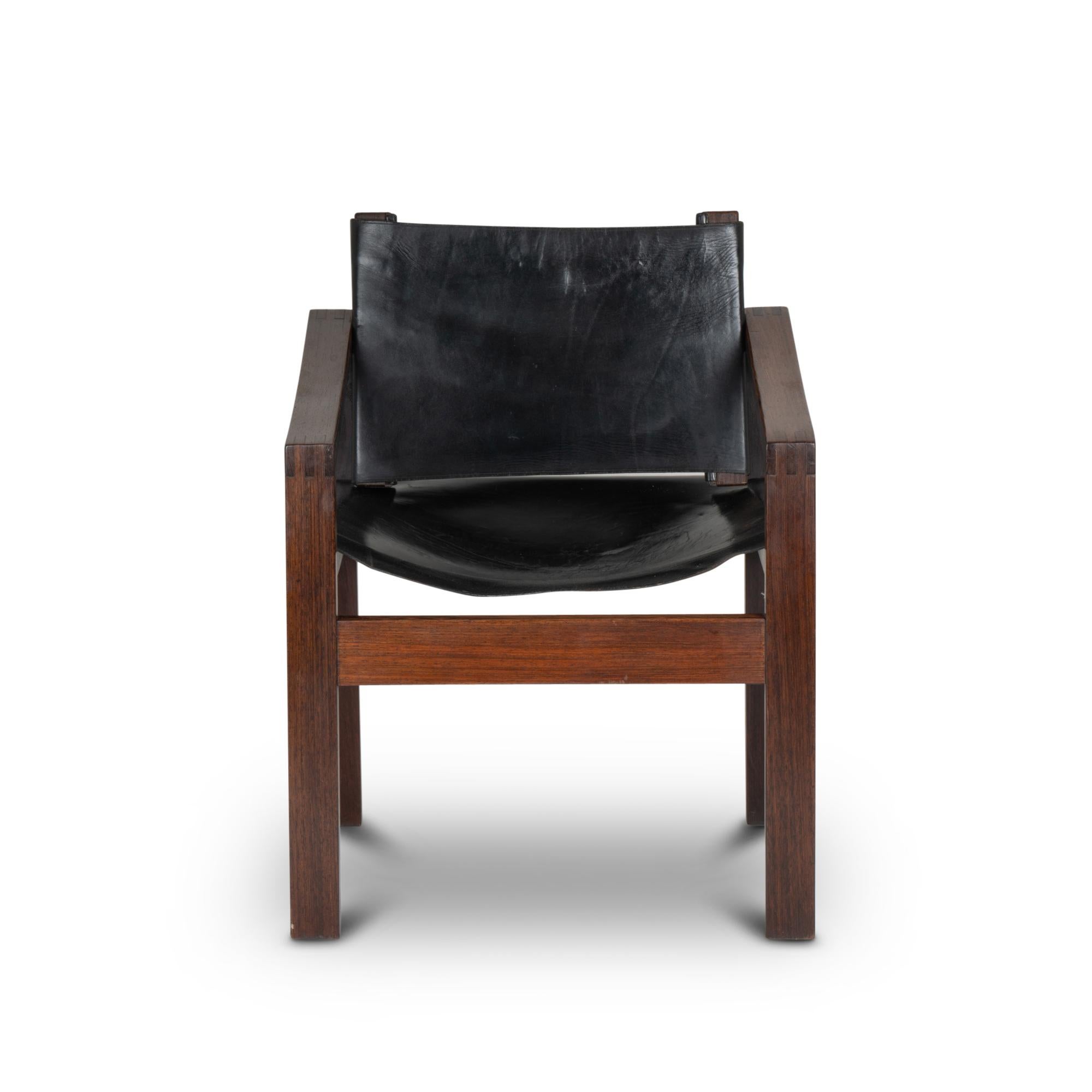 Armchair in rosewood, rectangular shape. Seat and back in black leather, the back being slightly curved.

Work realized in the 1970s.
