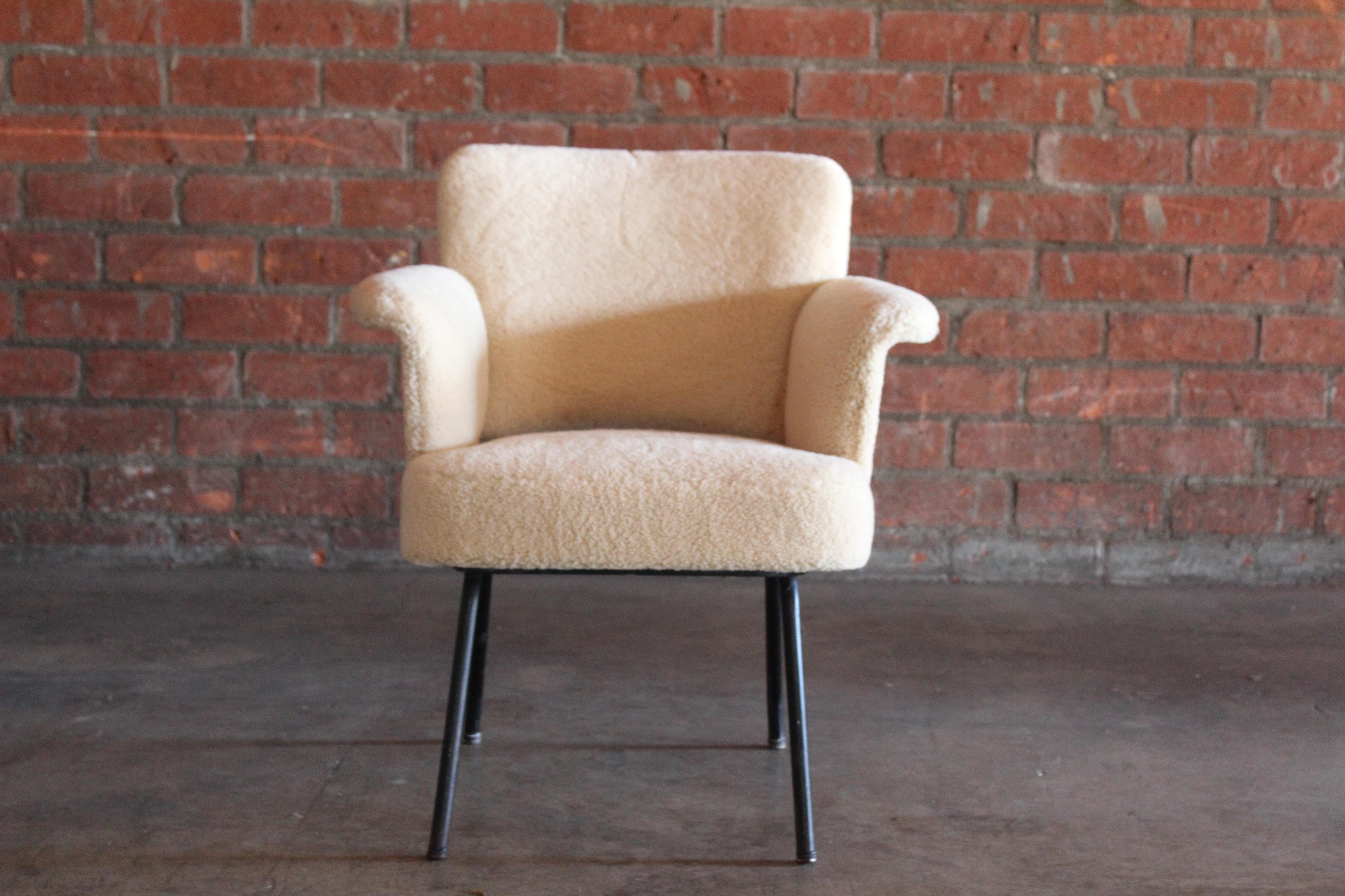 A vintage mid-century armchair by Pierre Guariche, France, 1950s. Newly upholstered in sheepskin. The metal legs are in their original condition with a nice patina. We have a pair, sold individually. This chair is two inches lower than the other