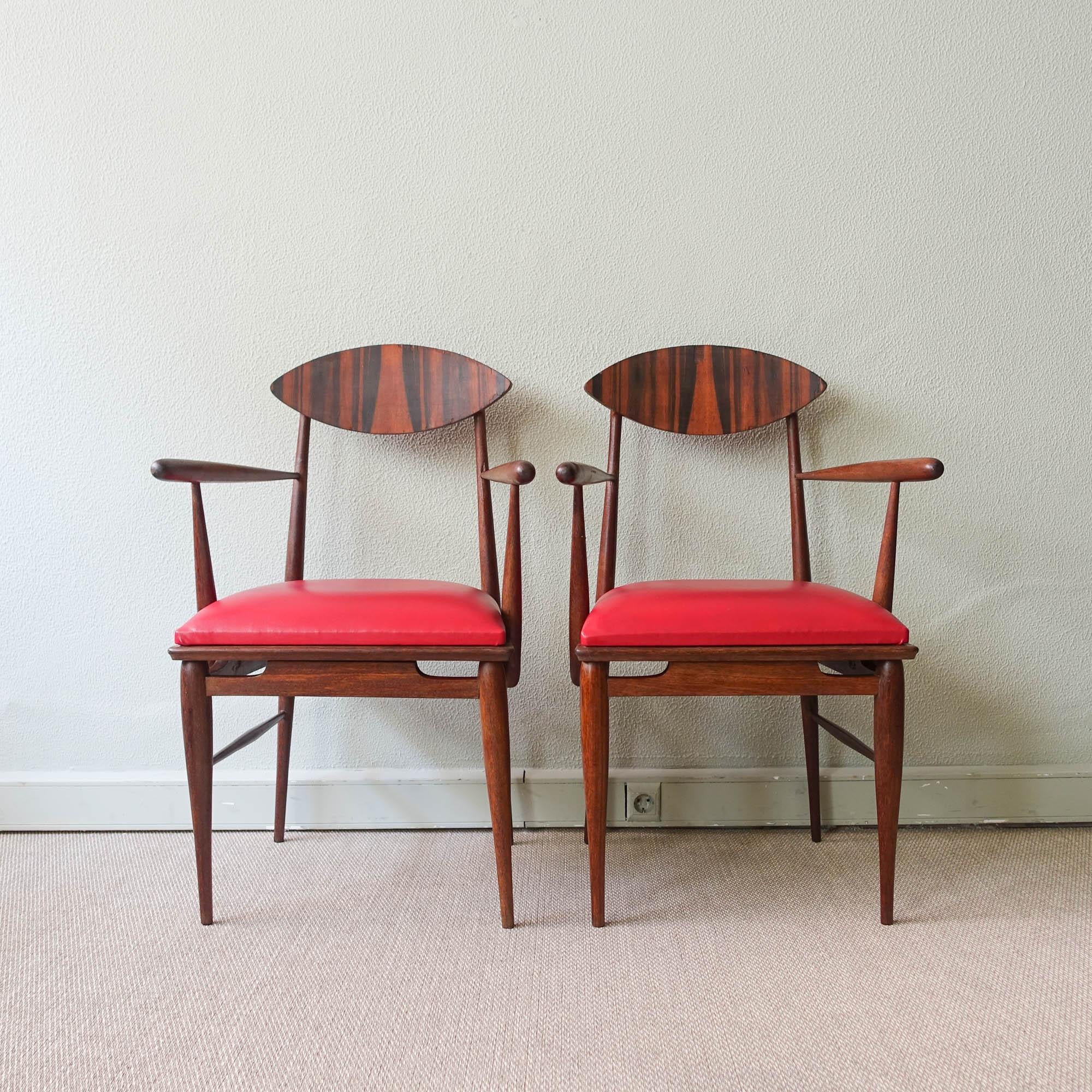 This pair of armchairs was designed and produced in Portugal during the 1950's. They feature a sucupira wood structure, with bent curved back and the seat is upholstered with a red synthetic leather.The chairs have a simple, modernist silhouette,