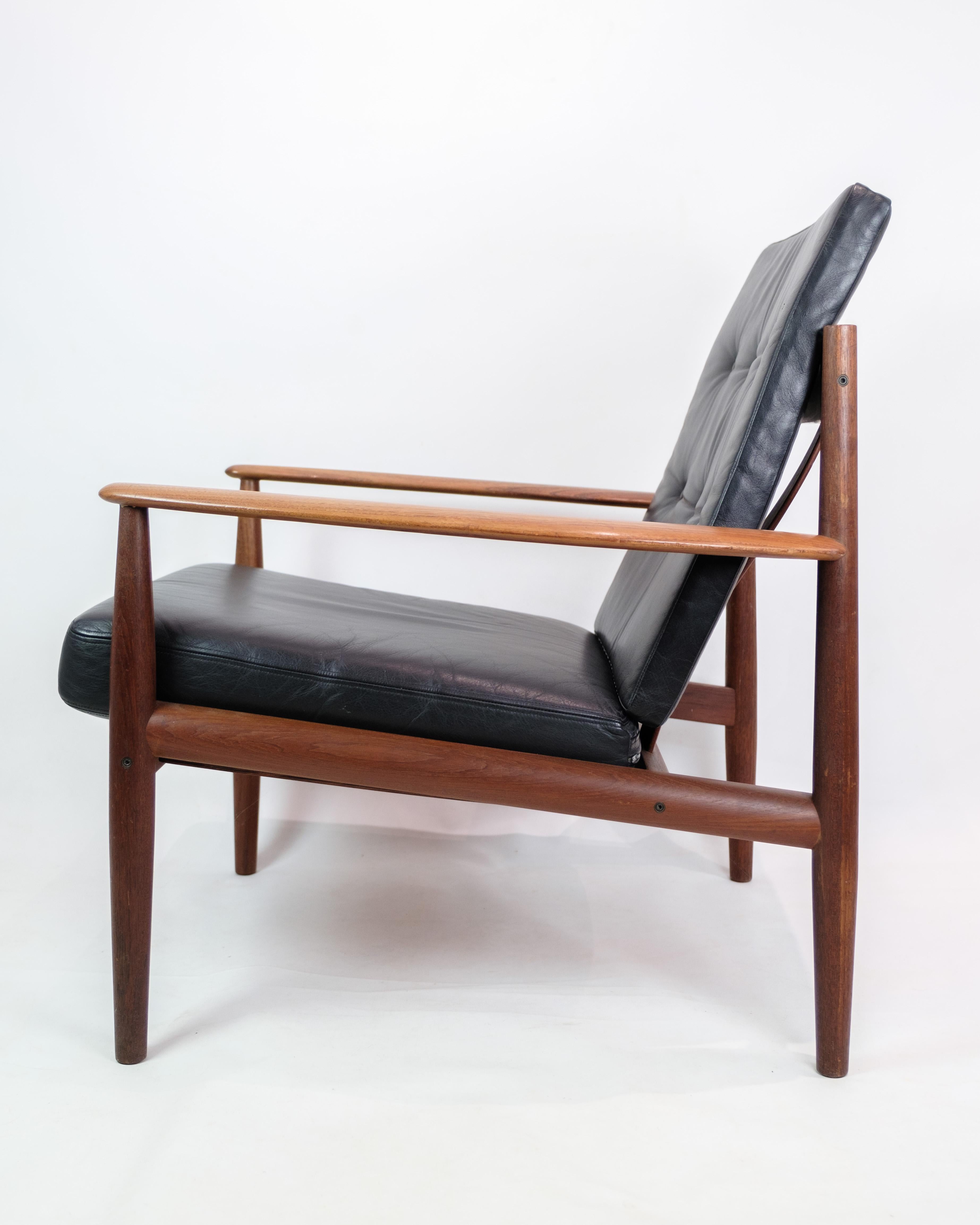 Profitez d'une expérience de repos sophistiquée avec ce fauteuil de relaxation, modèle 118, conçu par la talentueuse Grete Jalk et fabriqué par France & Son dans les années 1960. Fabriquée en teck et en élégant cuir noir, cette chaise est un