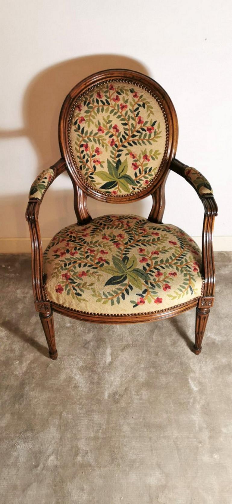 Comfortable walnut armchair; the back is large and comfortable; the walnut structure is worked with a sober and elegant Napoleon III style; the upholstery is original, nailed with studs and masterfully handmade with needlepoint with colorful flowers