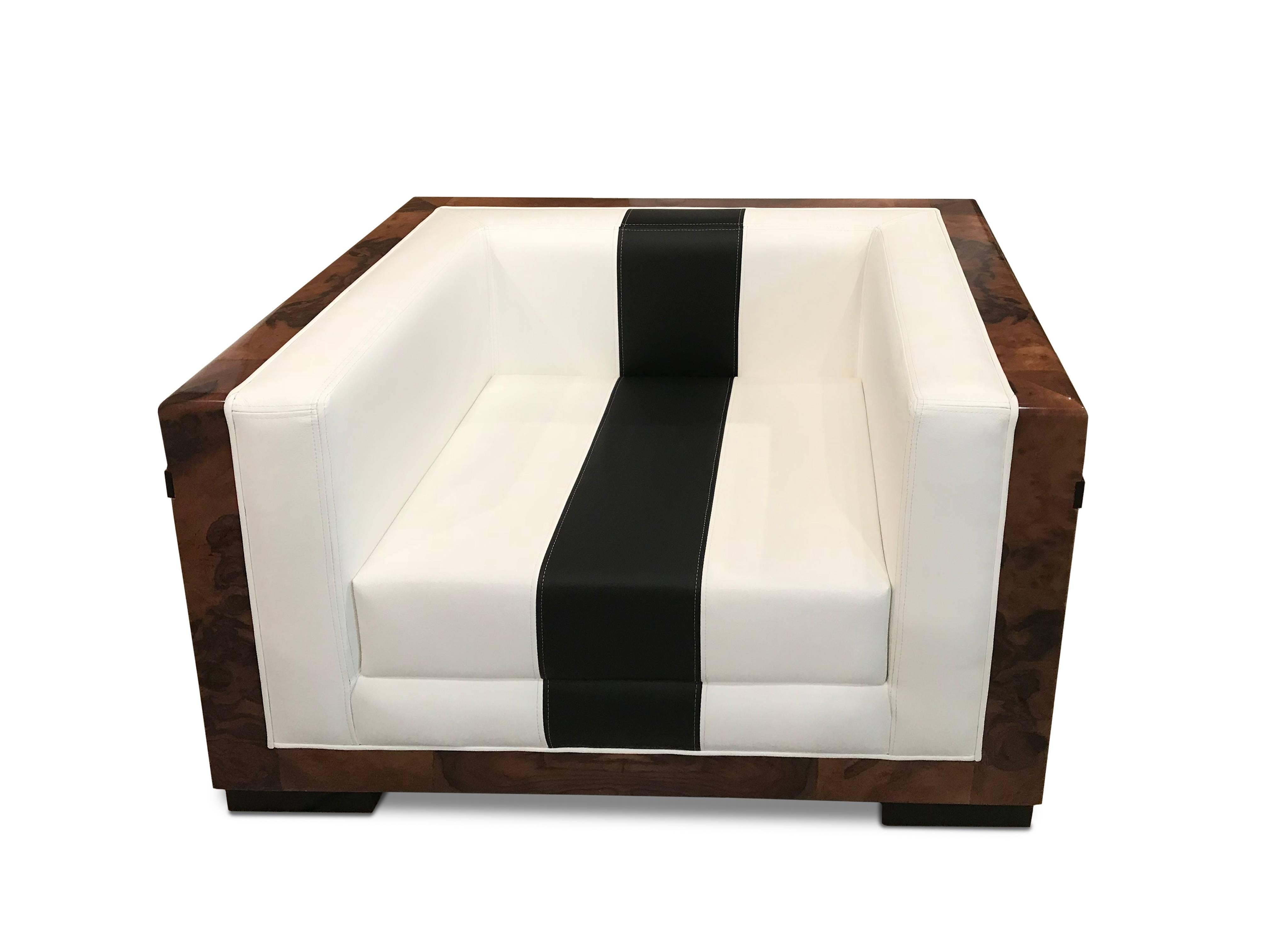 Solid armchair with walnut veneer finished in a high gloss varnish accented with black linear insets of ebony. Upholstered in white matte leather with black matte leather inset. Accented with contrasting stitching.