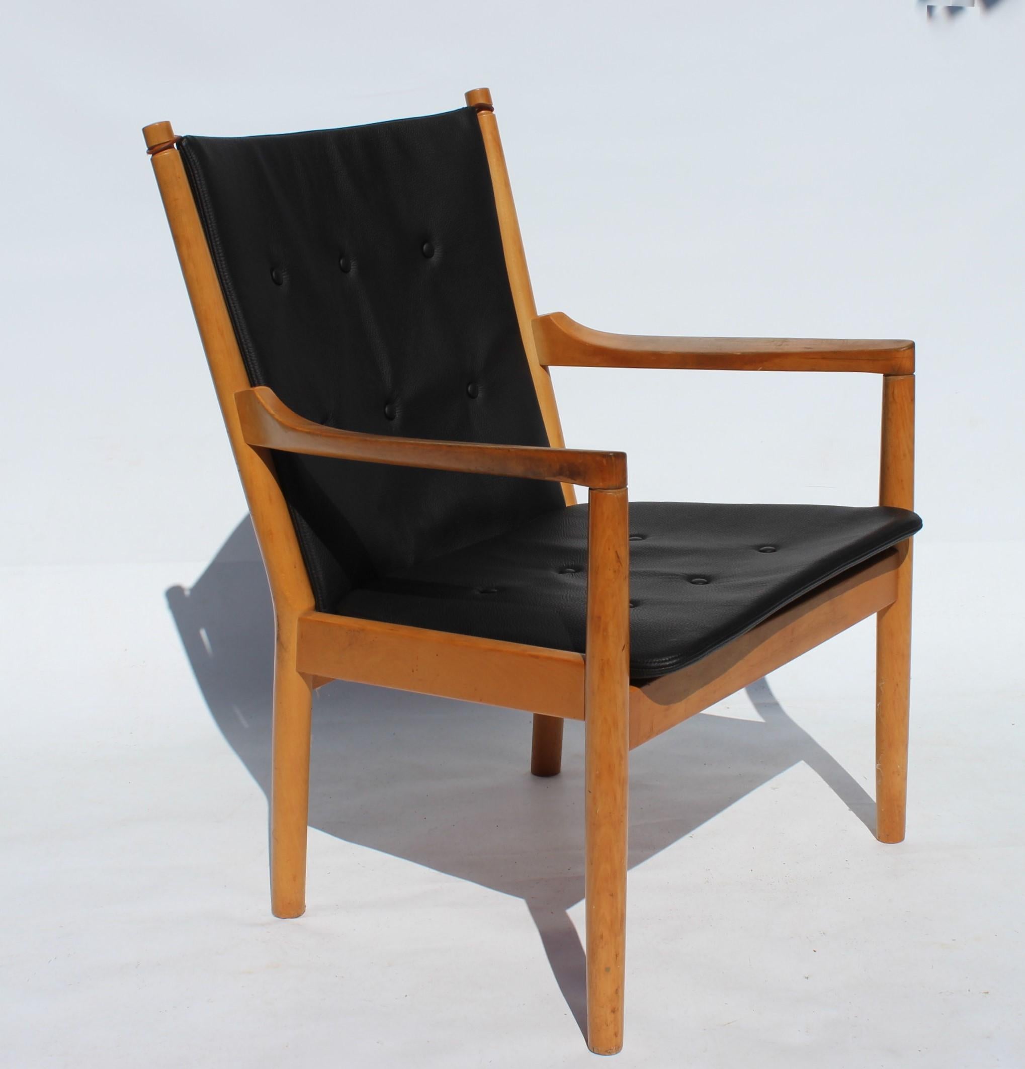 Le fauteuil, connu sous le nom de modèle 1788, est un meuble élégant avec un dossier emblématique en bois de hêtre et des coussins rembourrés en cuir noir. Conçue par le célèbre architecte et designer de meubles danois Hans J. Wegner en 1978 et