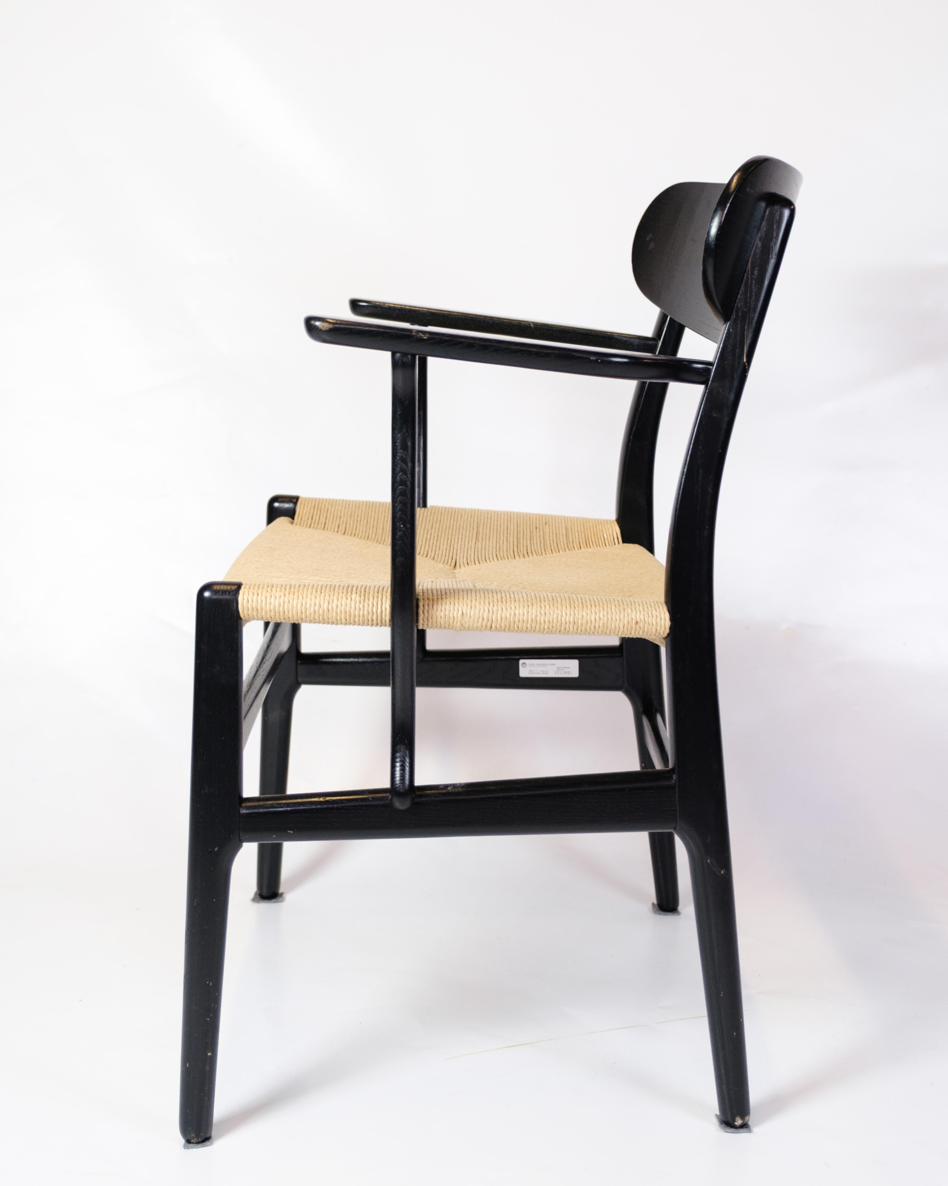 Sessel mit Armlehnen, Modellbezeichnung CH26 aus schwarzer Eiche mit hellem Papiergarn, hergestellt von Carl Hansen & Son. Der Stuhl CH26 ist ein Entwurf von Hans J. Wegner aus den 1950er Jahren und aufgrund der geschwungenen Formen einer der