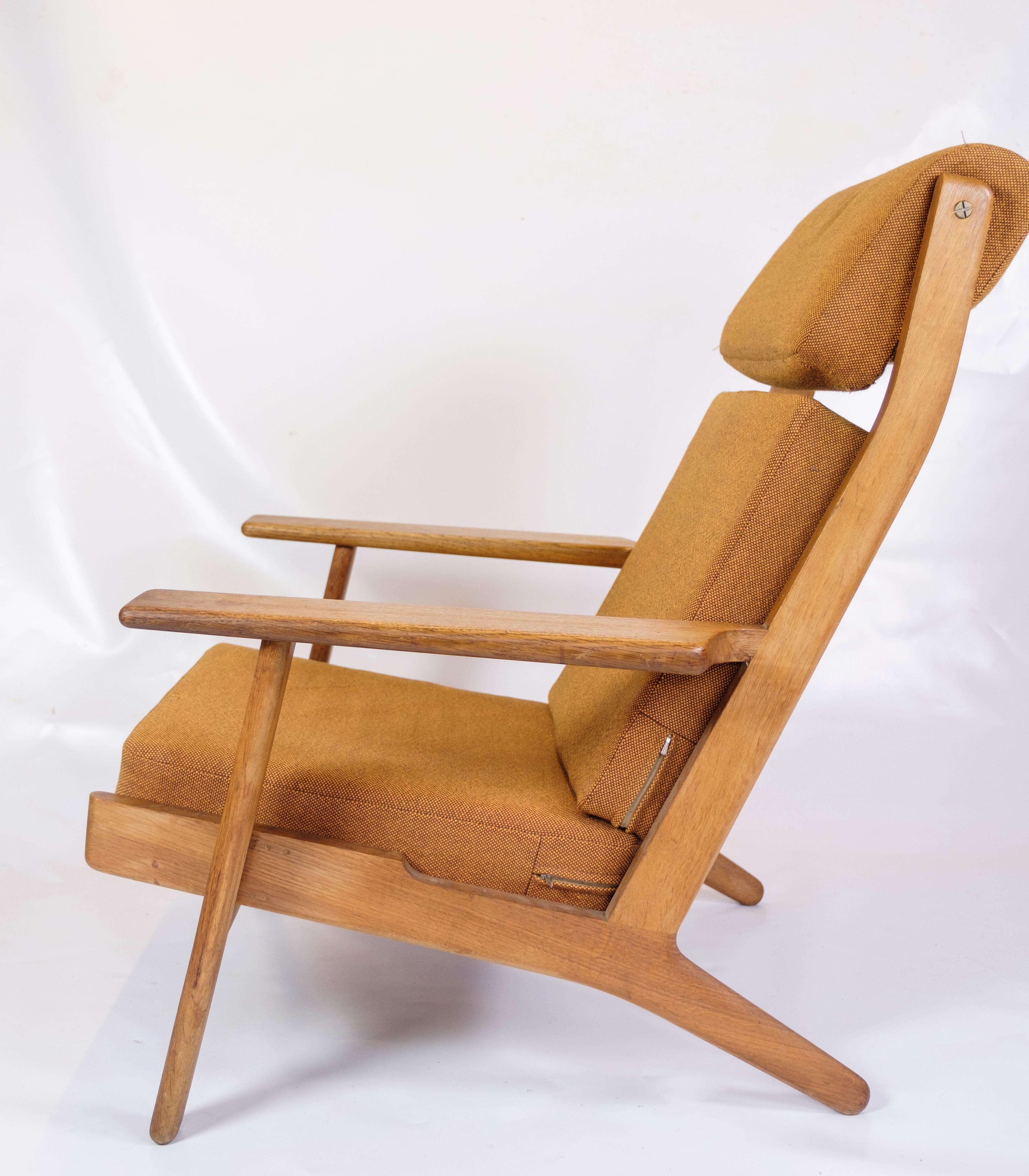 Questa poltrona, modello GE290A con schienale alto, disegnata da Hans J. Wegner e prodotta da Getama negli anni '60, è un eccellente esempio di design danese della metà del secolo scorso. La sedia combina il legno massiccio di Oak con il tessuto