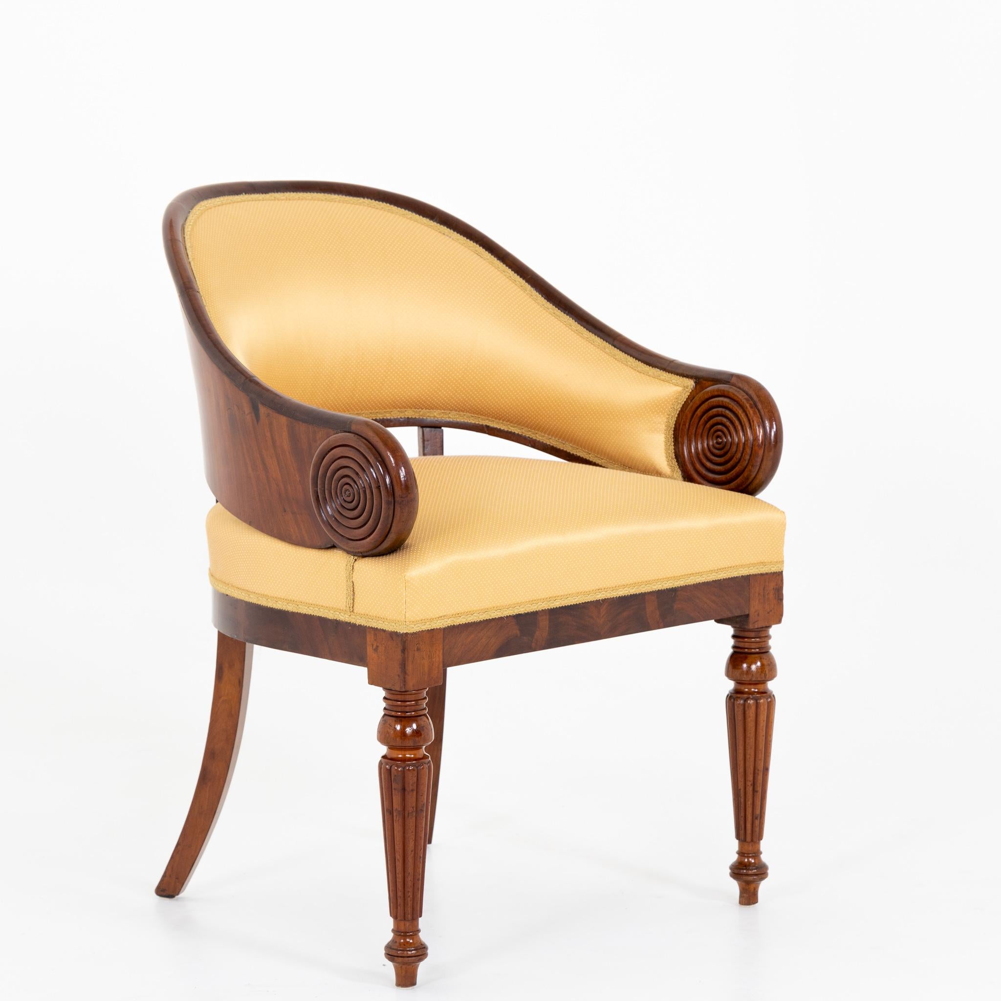 Armchair with rounded back and carved ring-shaped decorations standing on baluster legs. Mahogany, veneered and solid; reupholstered.