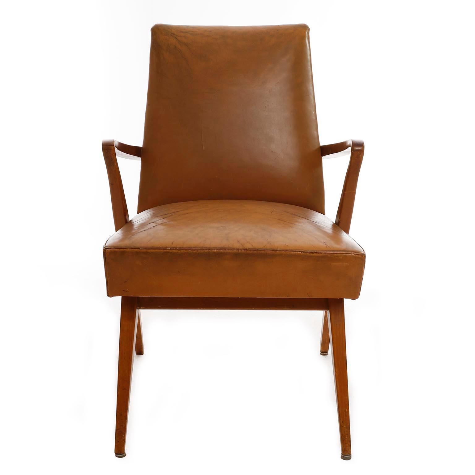 An armchair manufactured in midcentury in Austria, circa 1950.
The piece is made of a wooden base with an upholstery in leather with great patina. Patinated brass studs at the back.
Noticeable wear on leather and wood. Wrinkles and scratches in