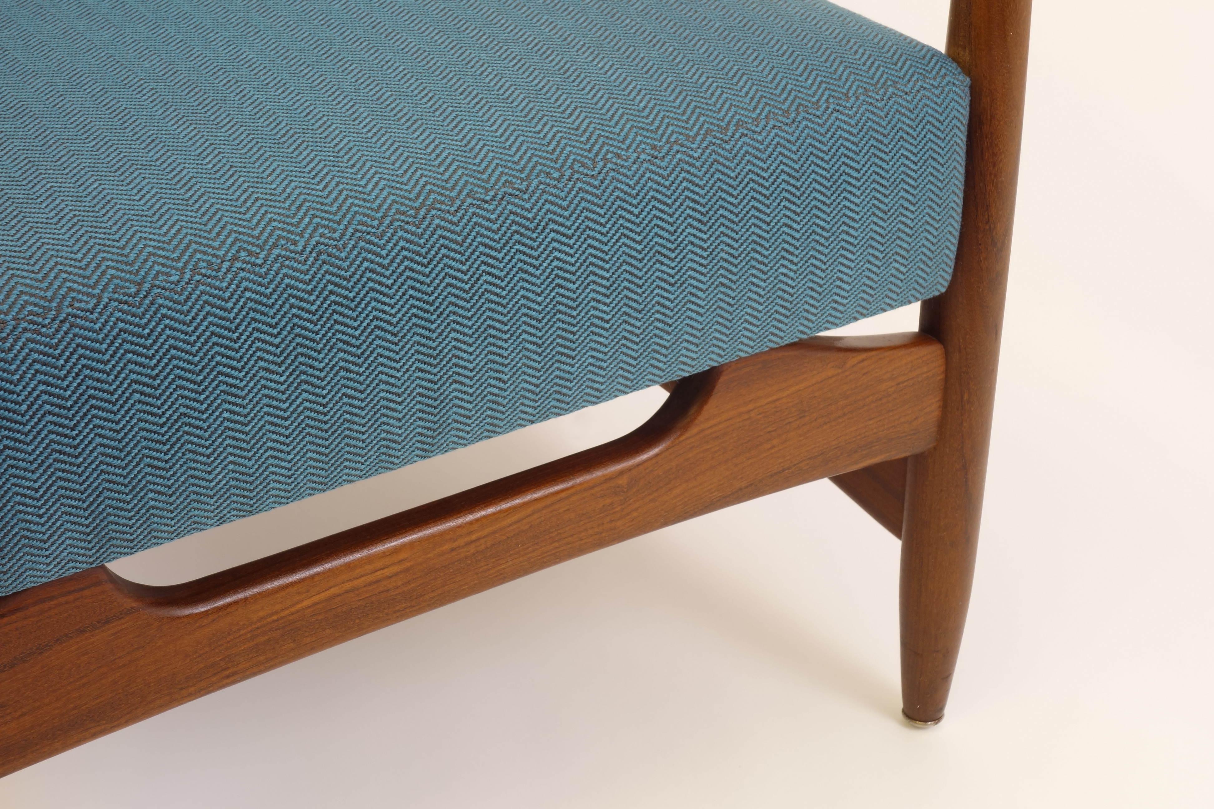 Ein bezaubernder Sessel mit authentischem dänischen Design in einer mehr als geschmackvollen Farbkomposition. Die Polsterung wurde neu mit einem tealfarbenen Stoff mit Fischgrätmuster bezogen, der einen subtilen Kontrast zum warmen Holzton bildet.