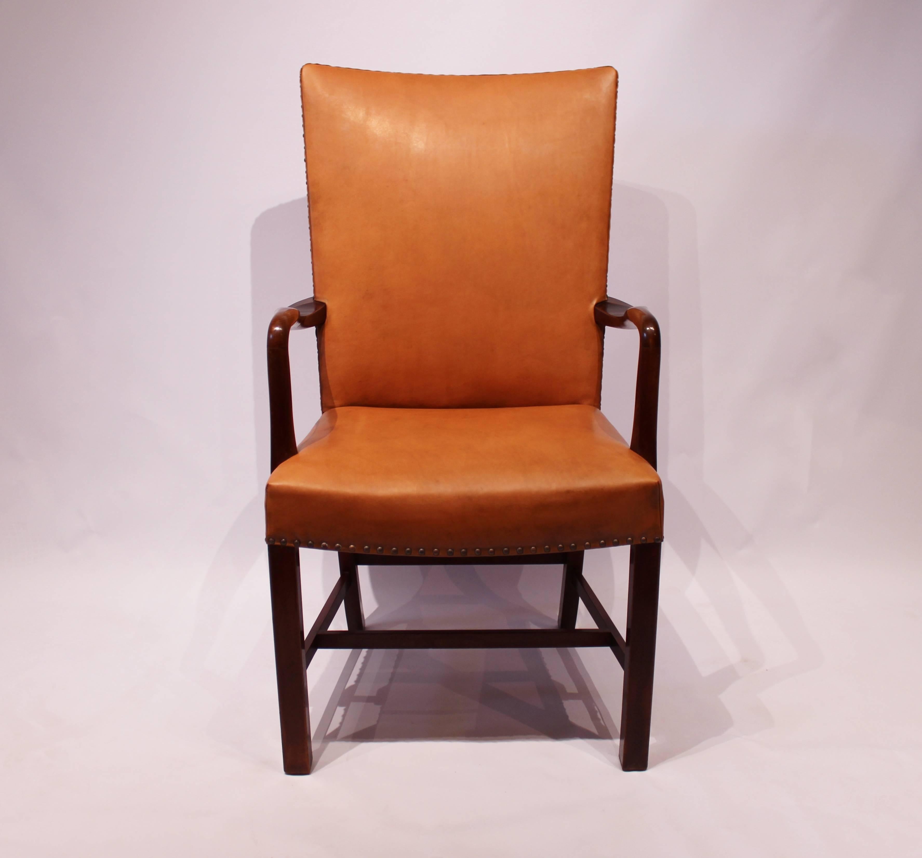 
An armchair upholstered in cognac-colored Elegance leather with polished dark wood and brass pins, designed by Fritz Hansen in 1944, showcases a beautiful blend of classic design and luxurious materials.

Fritz Hansen is a well-known Danish
