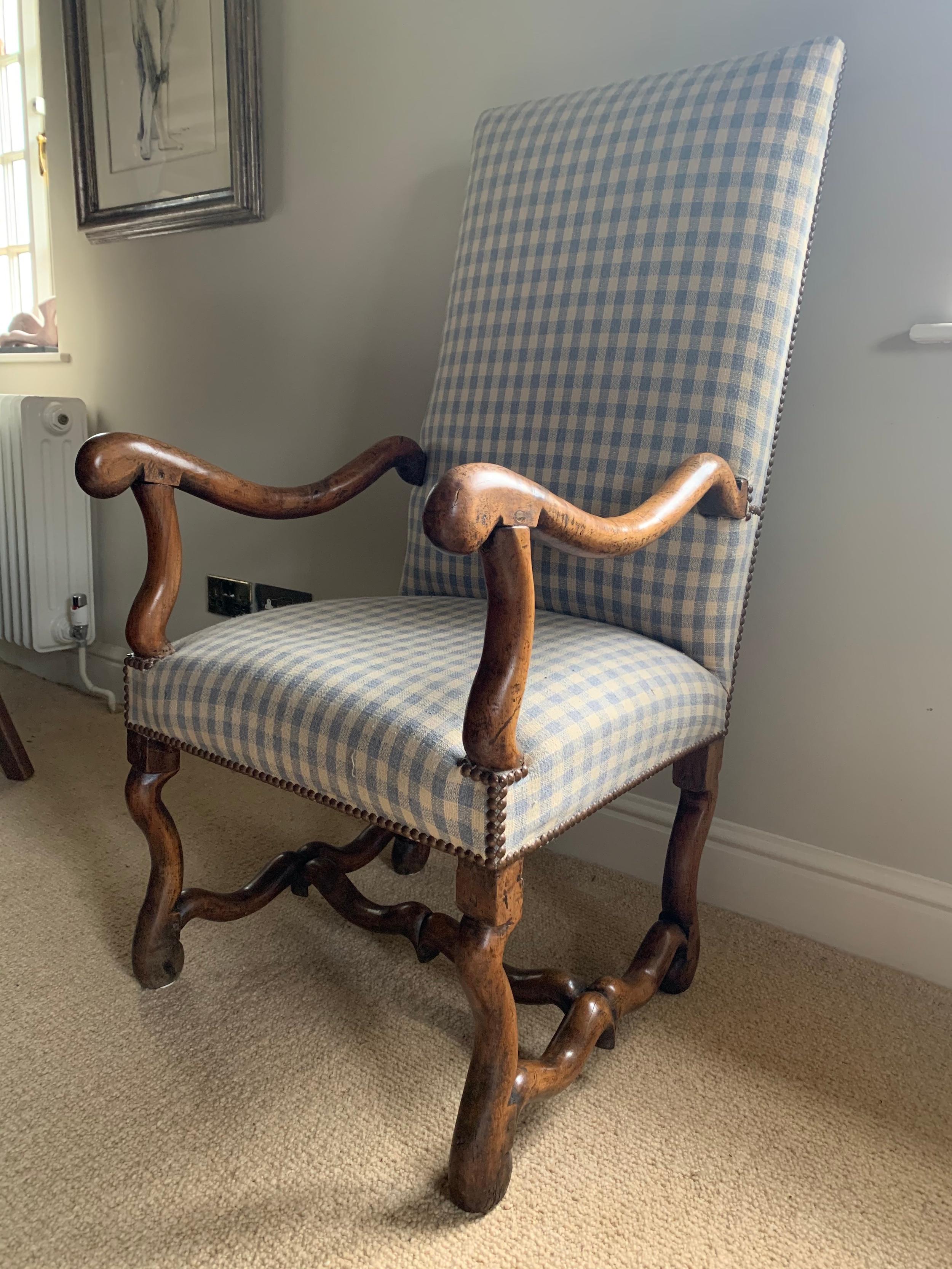 The outside and inside rectangular back and seat re-upholstered, during its last ownership, with an off-white and grey/blue cotton/linen mix fabric faced with close nailed brass studs. The walnut scroll arms are supported scroll uprights on ‘os de
