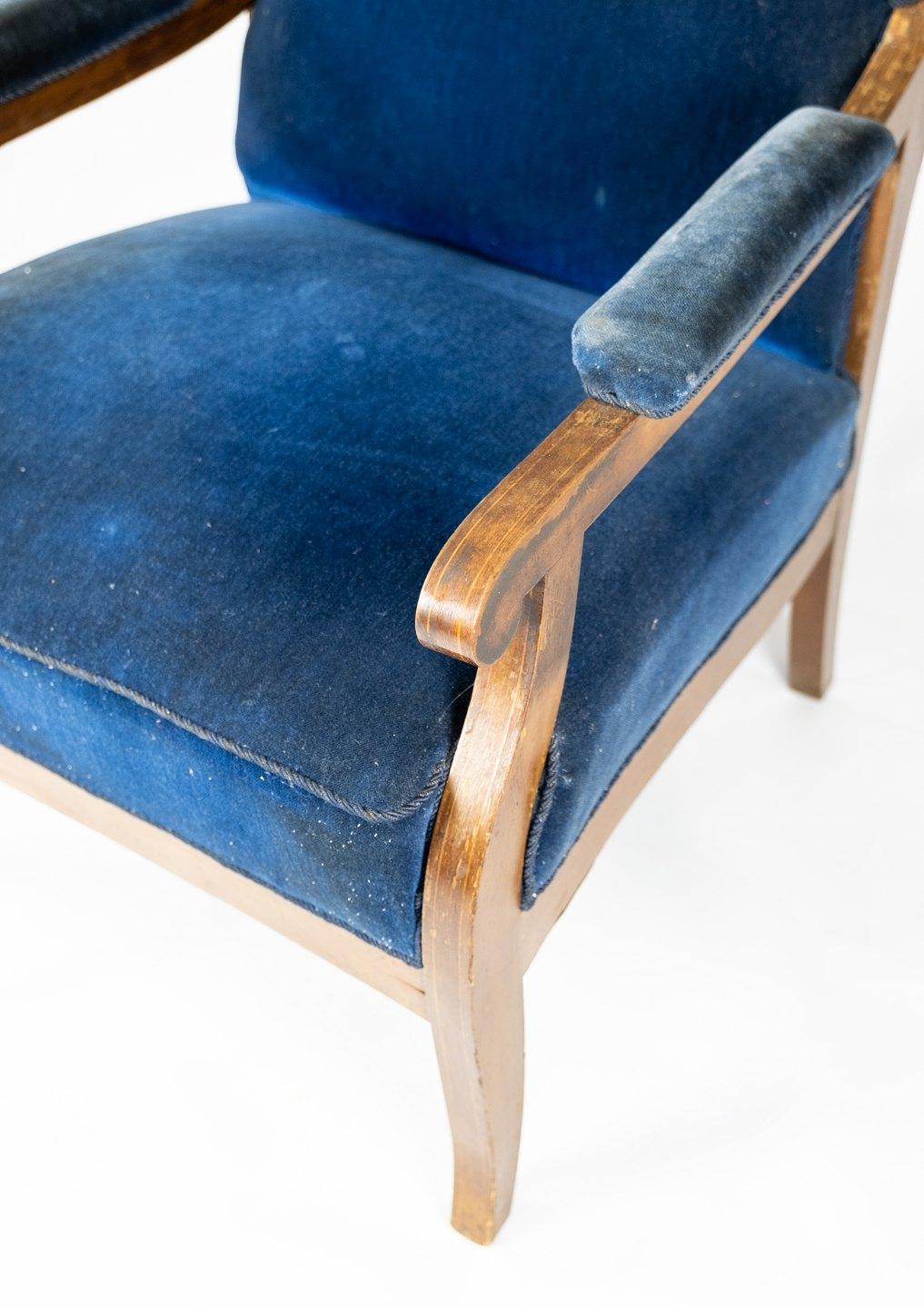 Le fauteuil, conçu par Fritz Henningsen, allie un confort luxueux à une élégance intemporelle. Revêtu d'un somptueux velours bleu et fabriqué en acajou, il respire la sophistication et le raffinement. L'attention méticuleuse de Henningsen pour les