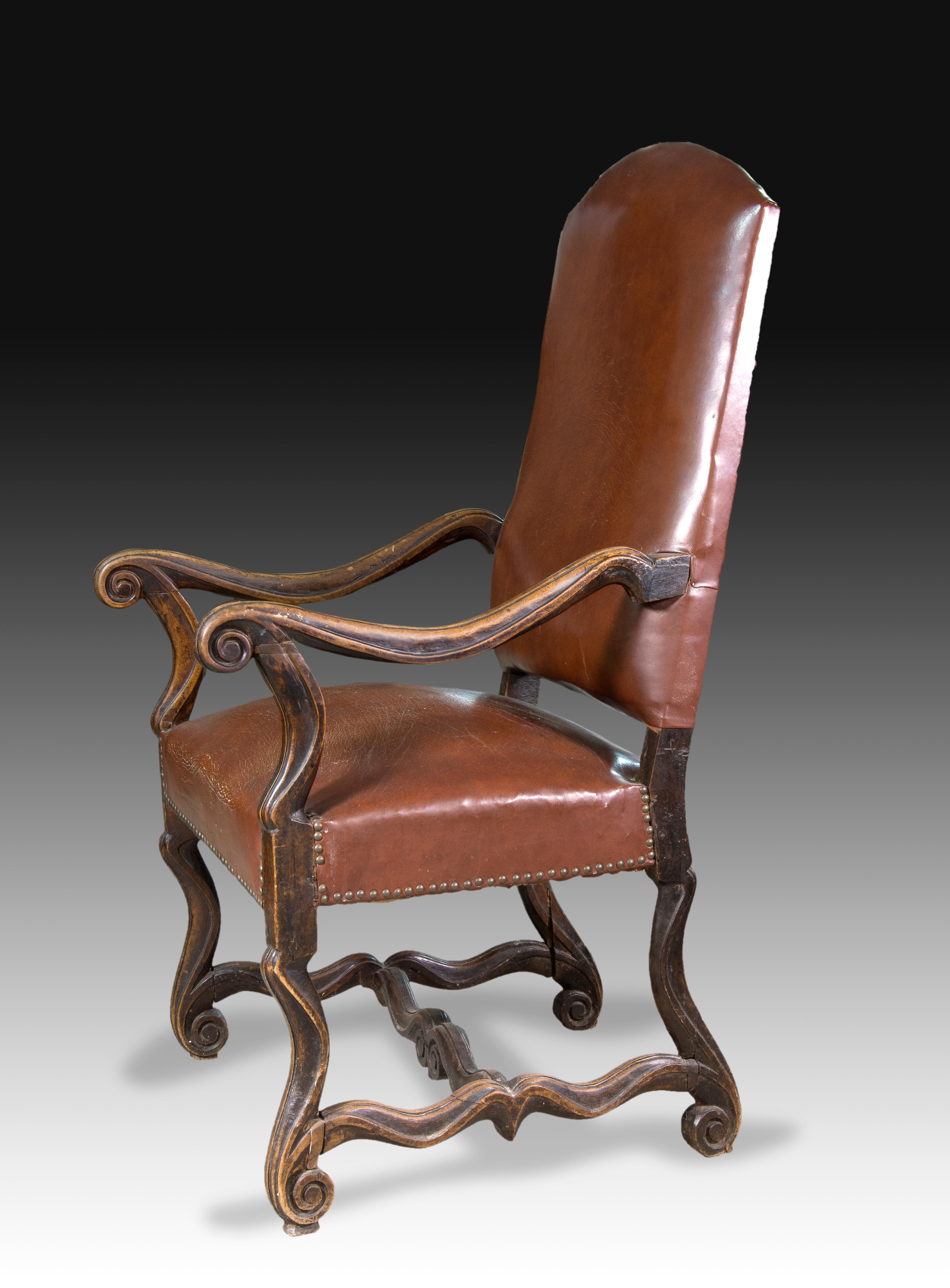 Fauteuil. Bois de Wood, cuir, 18e siècle. 
Fauteuil tapissé à haut dossier (comme l'assise, tous deux avec des clous), avec des accoudoirs en bois sculpté formant des vagues, qui a également des pieds courbés avec des volutes simples et un montant