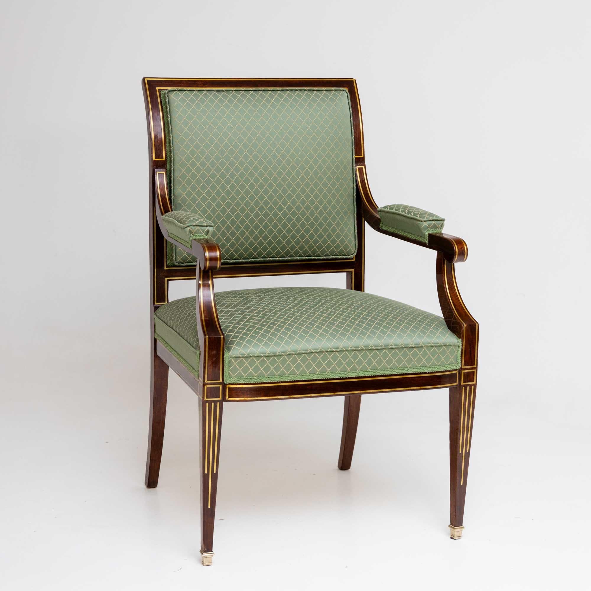 Sessel aus Mahagoni mit dekorativen Messingfadeneinlagen. Der Sessel steht auf eleganten, quadratischen, spitz zulaufenden Füßen mit Messing-Sabots. Der Stuhl wurde aufwändig mit einem hellgrünen Stoff mit goldenem Rautenmuster neu gepolstert. Wie