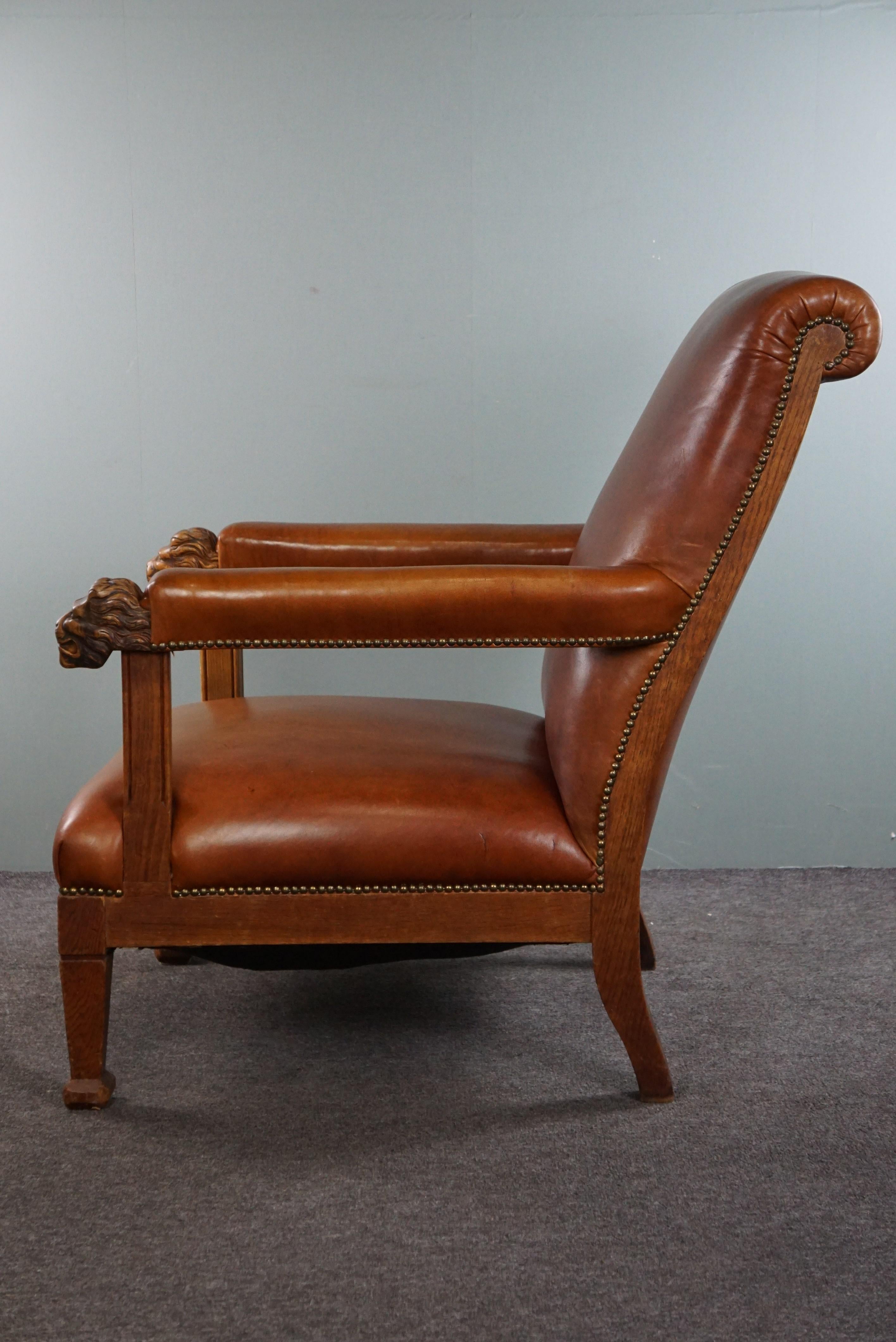 20ième siècle Fauteuil avec têtes de lion retapissé en cuir de vache de couleur cognac en vente