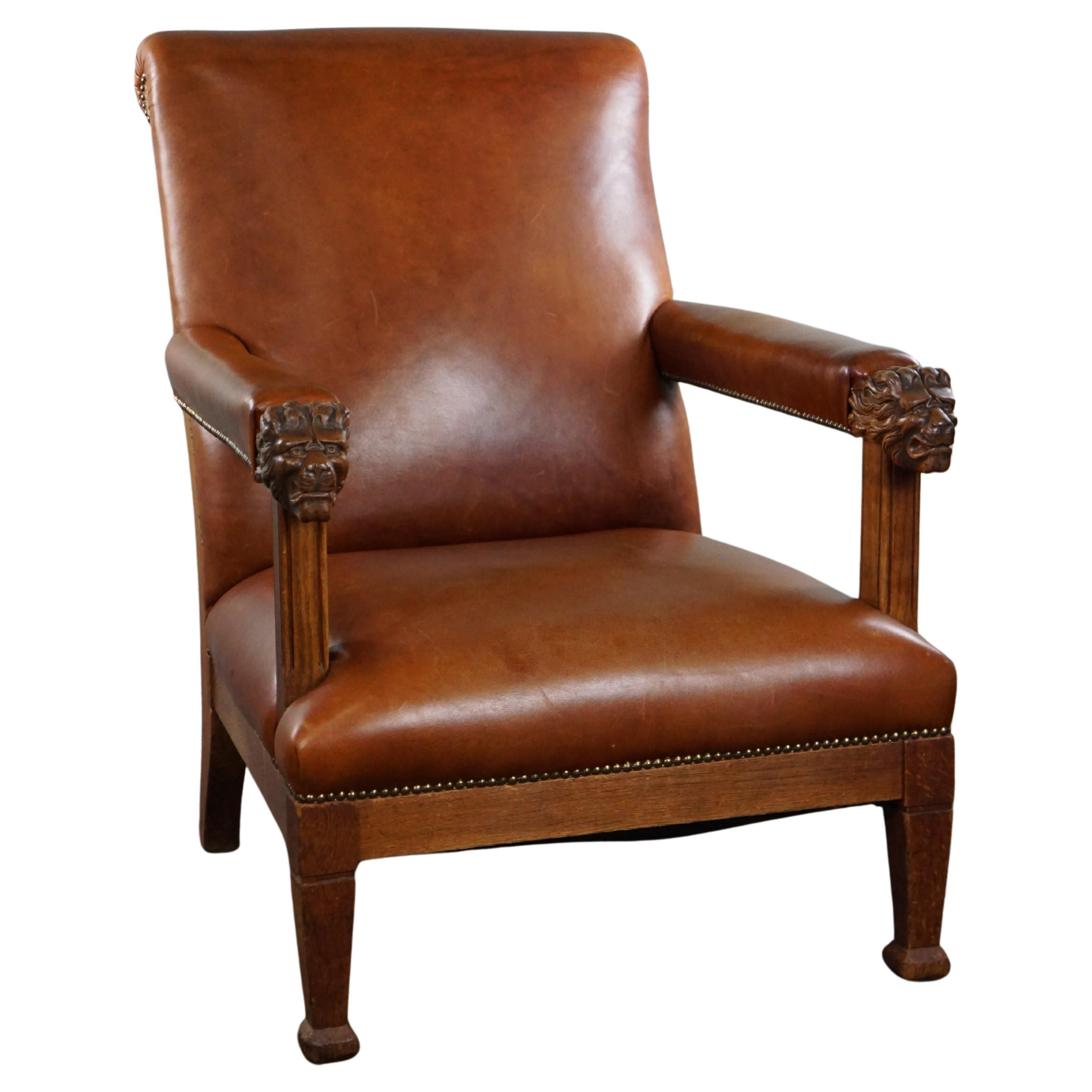 Armchair with lion heads reupholstered in cognac-colored cowhide For Sale