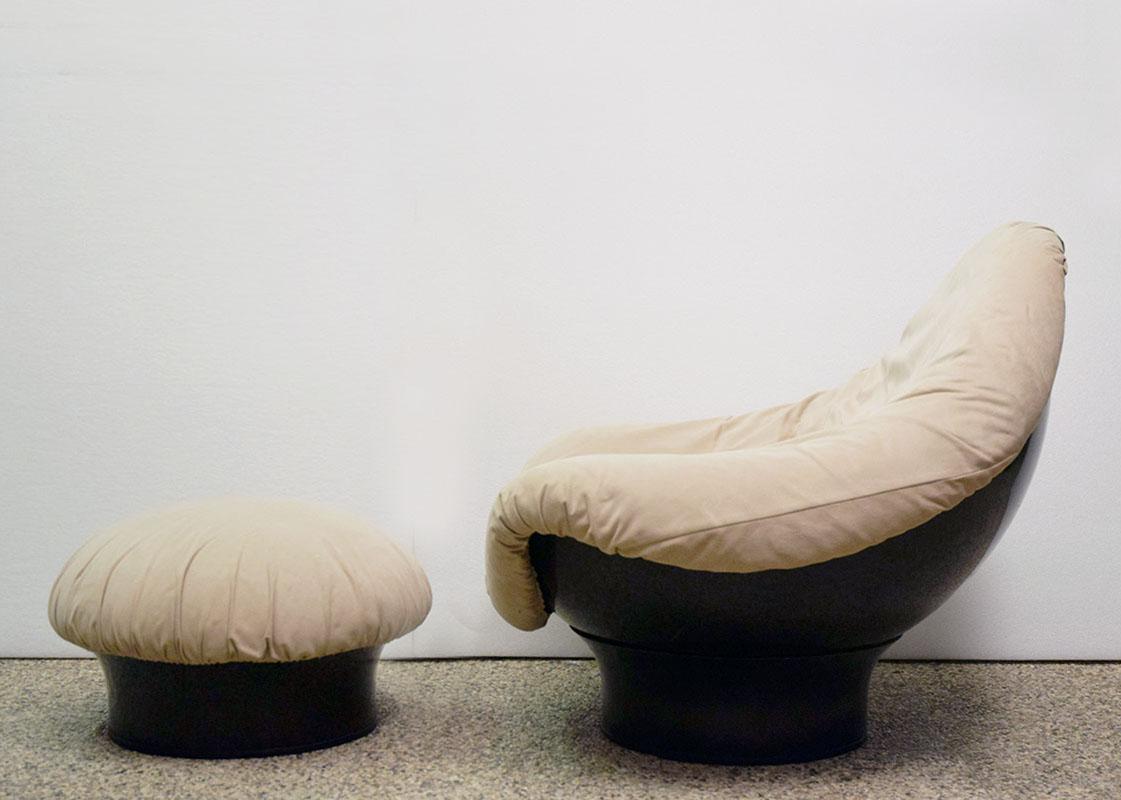 Poltrona con pouf modello Rodica disegnata da Mario Brunu per Comfort anni '70.
Scocca in fibra di vetro verniciata nera, poltrona e pouff rivestiti in pelle scamosciata beige.
La poltrona poggia sulla base ed è completamente mobile in modo da