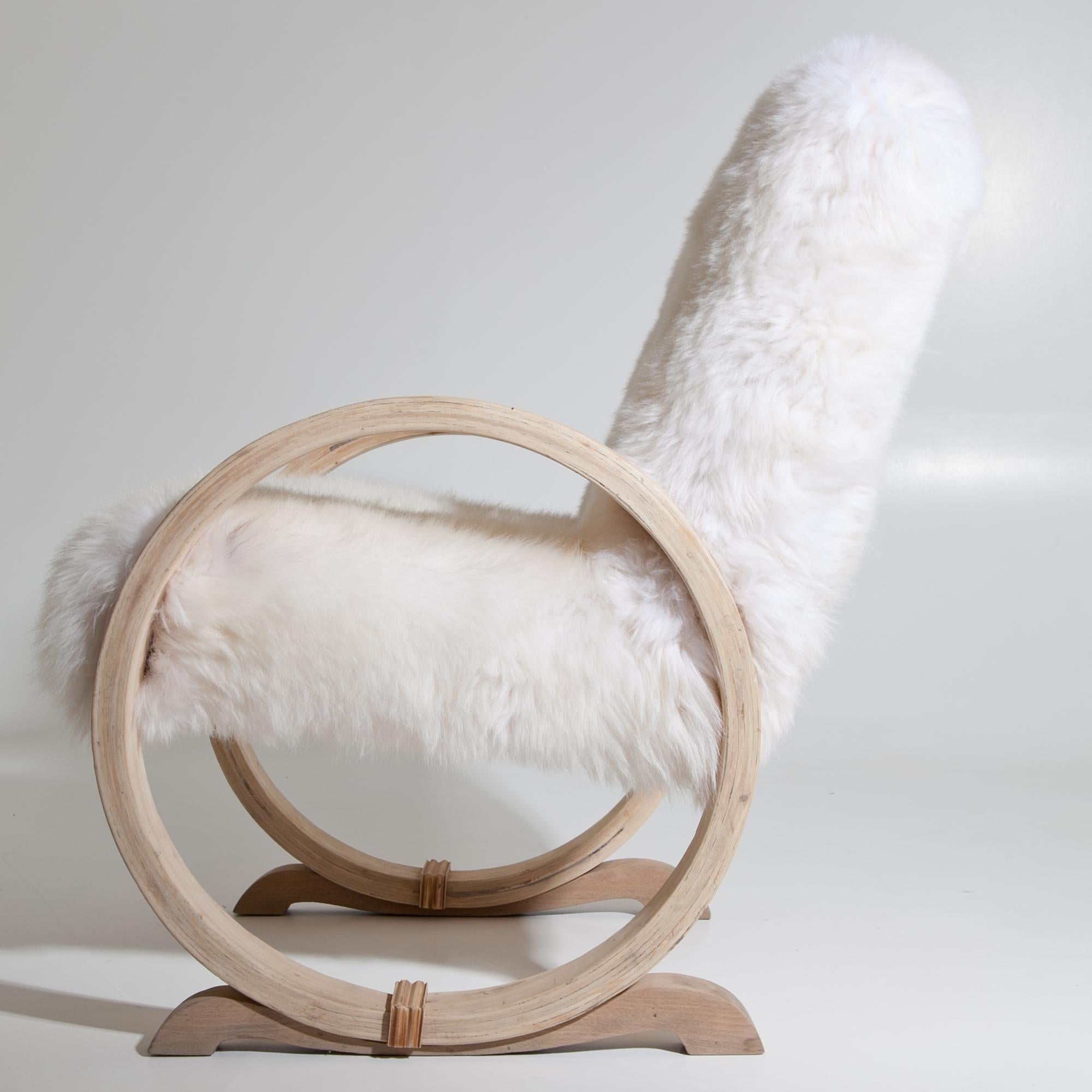 Armchair standing on hoops that serve as armrests. Seat and backrest were reupholstered with a white sheepskin.