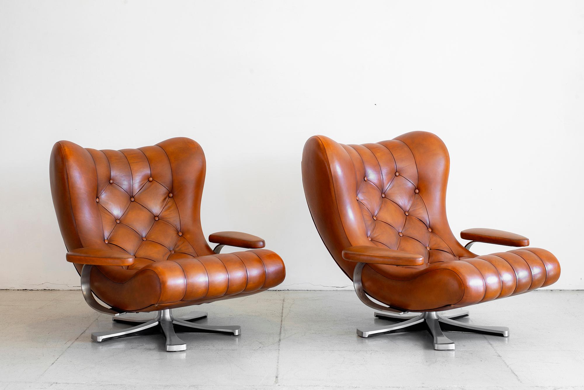 Paire de fauteuils de Guido Bonzanini pour Tecnosalotto, Italie, années 1970. De grands fauteuils touffus en cuir caramel nouvellement rembourré reposent sur des piétements en étoile en aluminium moulé sous pression et pivotant. 
Label du fabricant