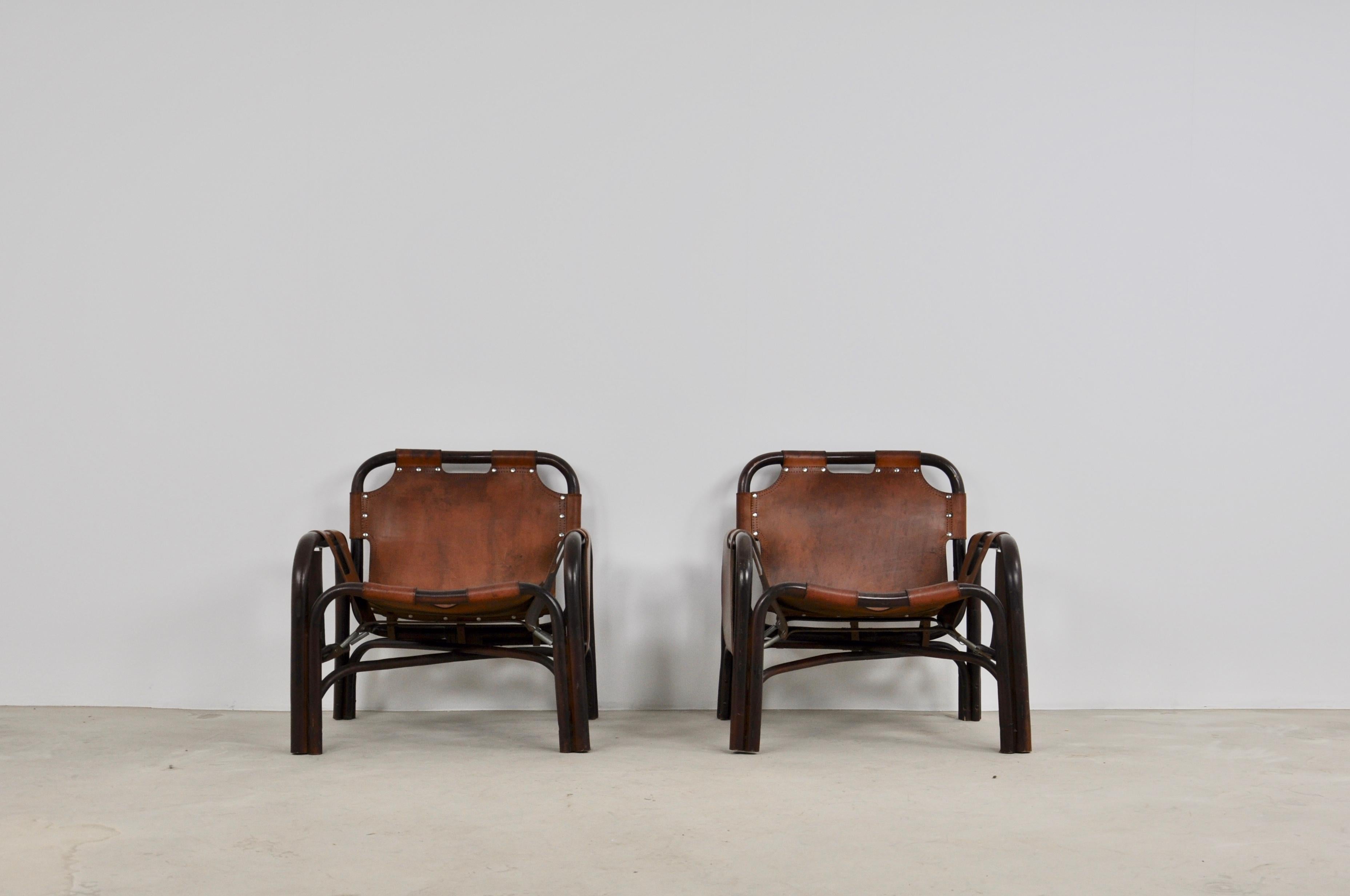 Pairs of leather and bamboo armchairs. Slight wear and tear due to time and use (see photo).