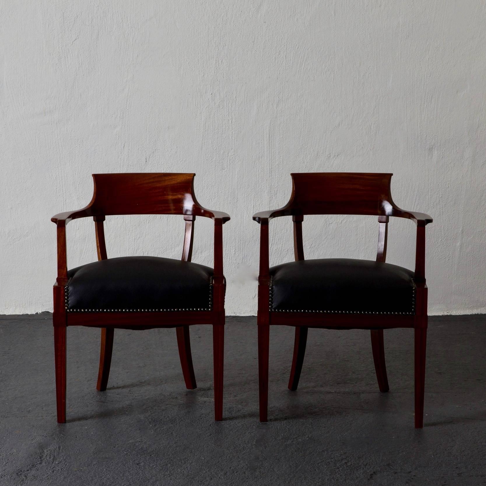 A pair of desk chairs made in Sweden during the 19th Century and Karl Johan period 1810-1830. Upholstered in a black soft leather. Height of Armrests: 25.5